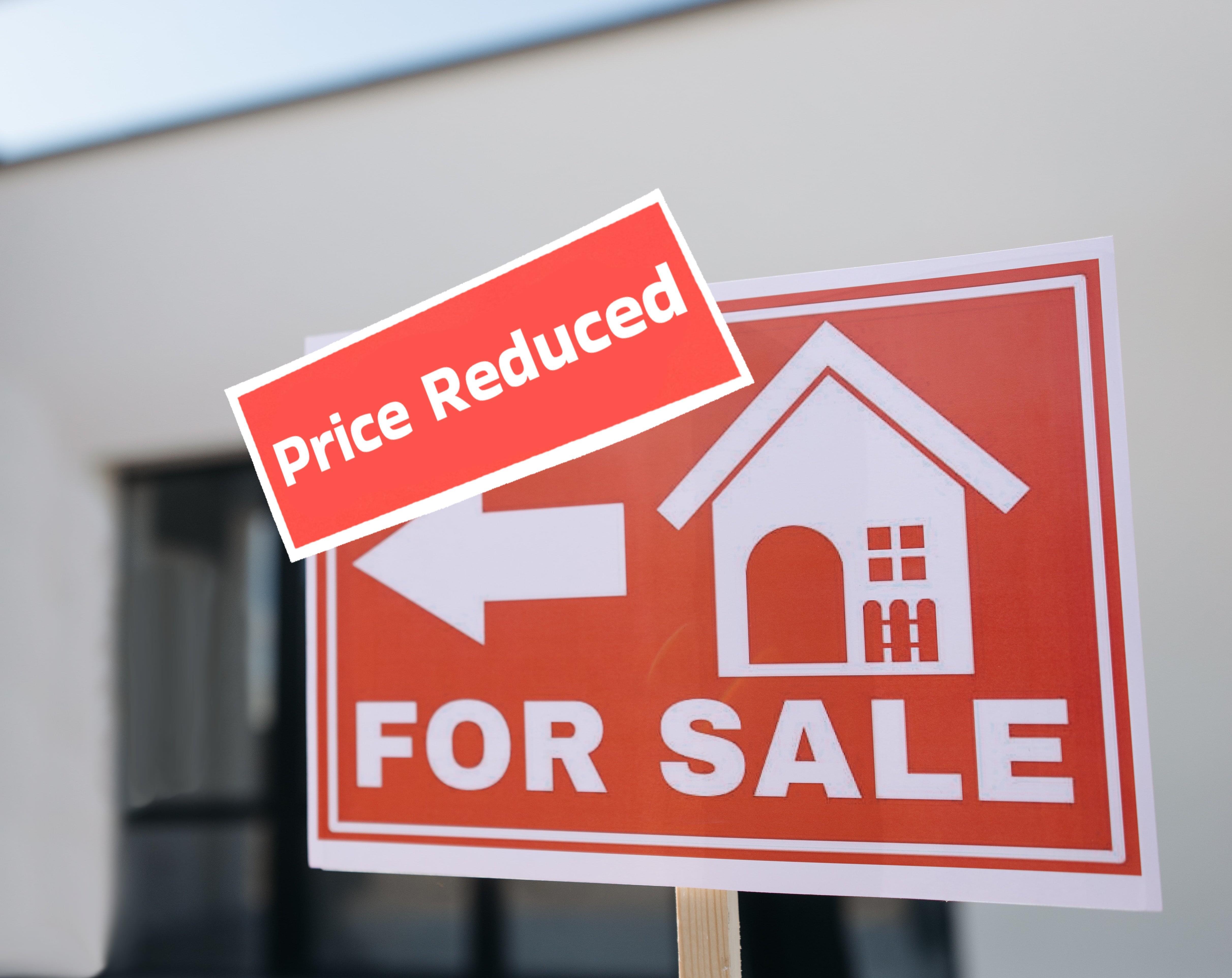 A house for sale sign with an additional price reduced sign