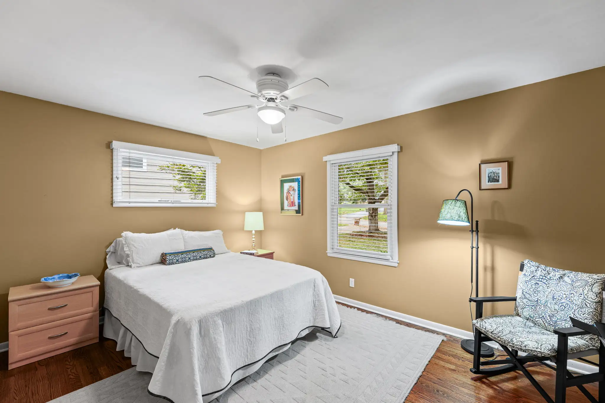 Bedroom with hardwood floors, two windows and a ceiling fan