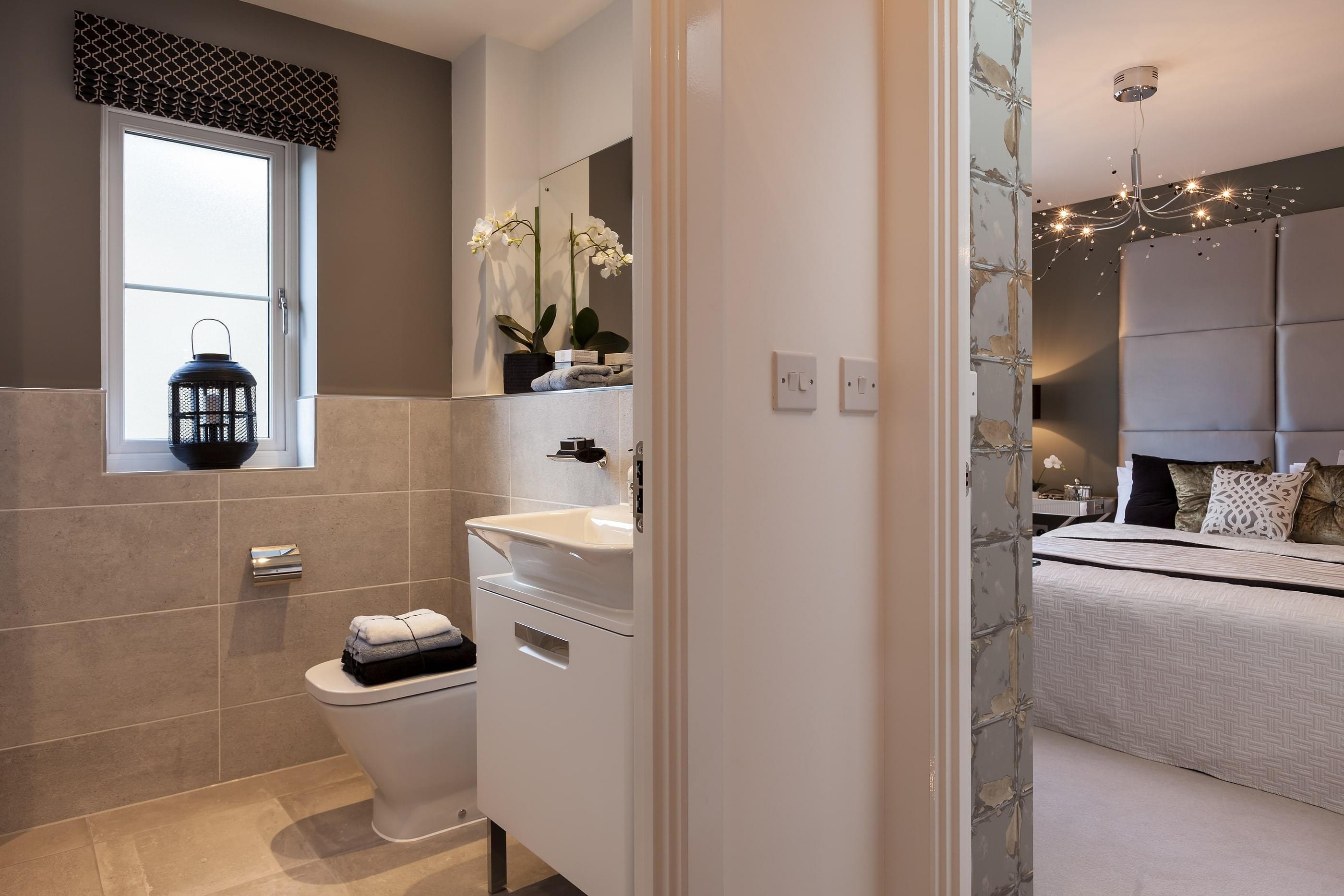 Contemporary modern show home bathroom ensuite to beautifully furnished bedroom beyond