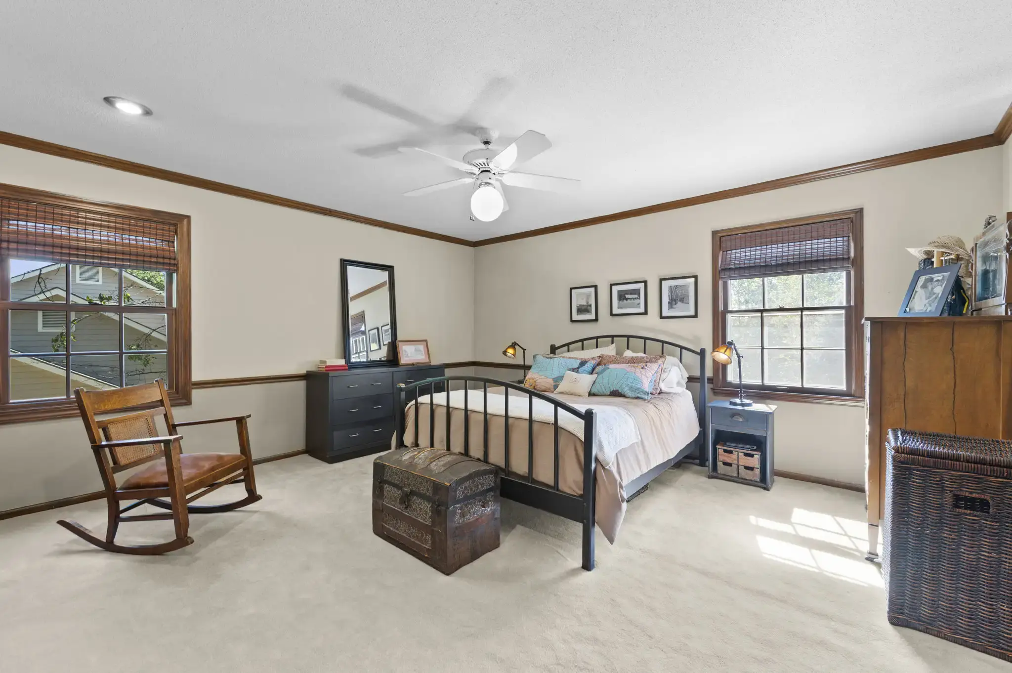 Primary bedroom with crown molding, ceiling fan and two windows