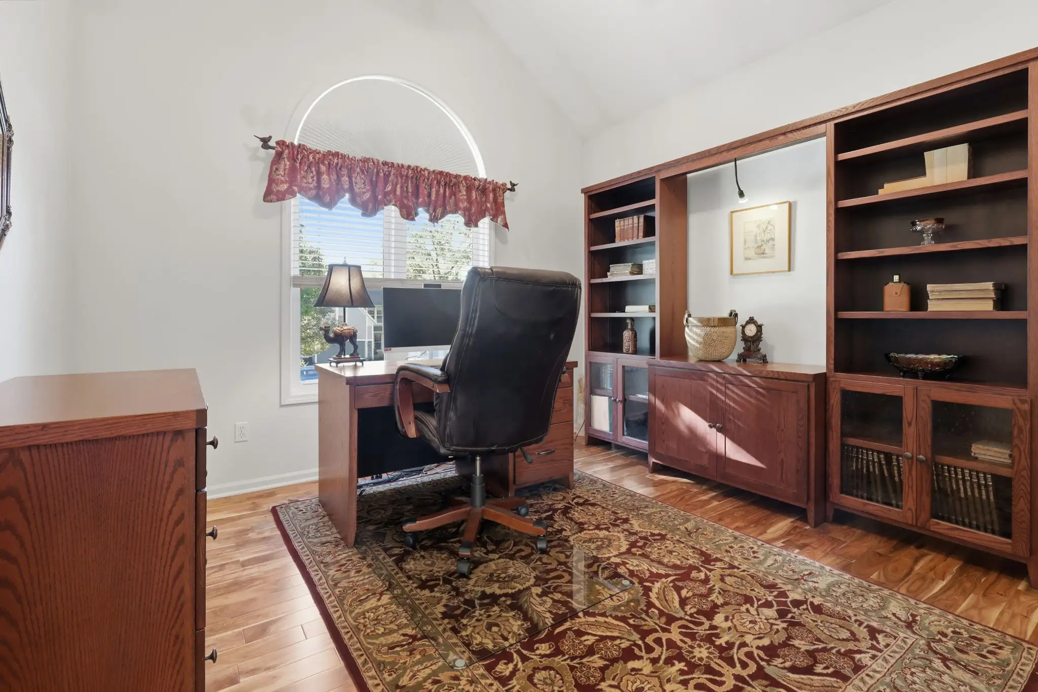 Vaulted bedroom with arched window set up as a home office