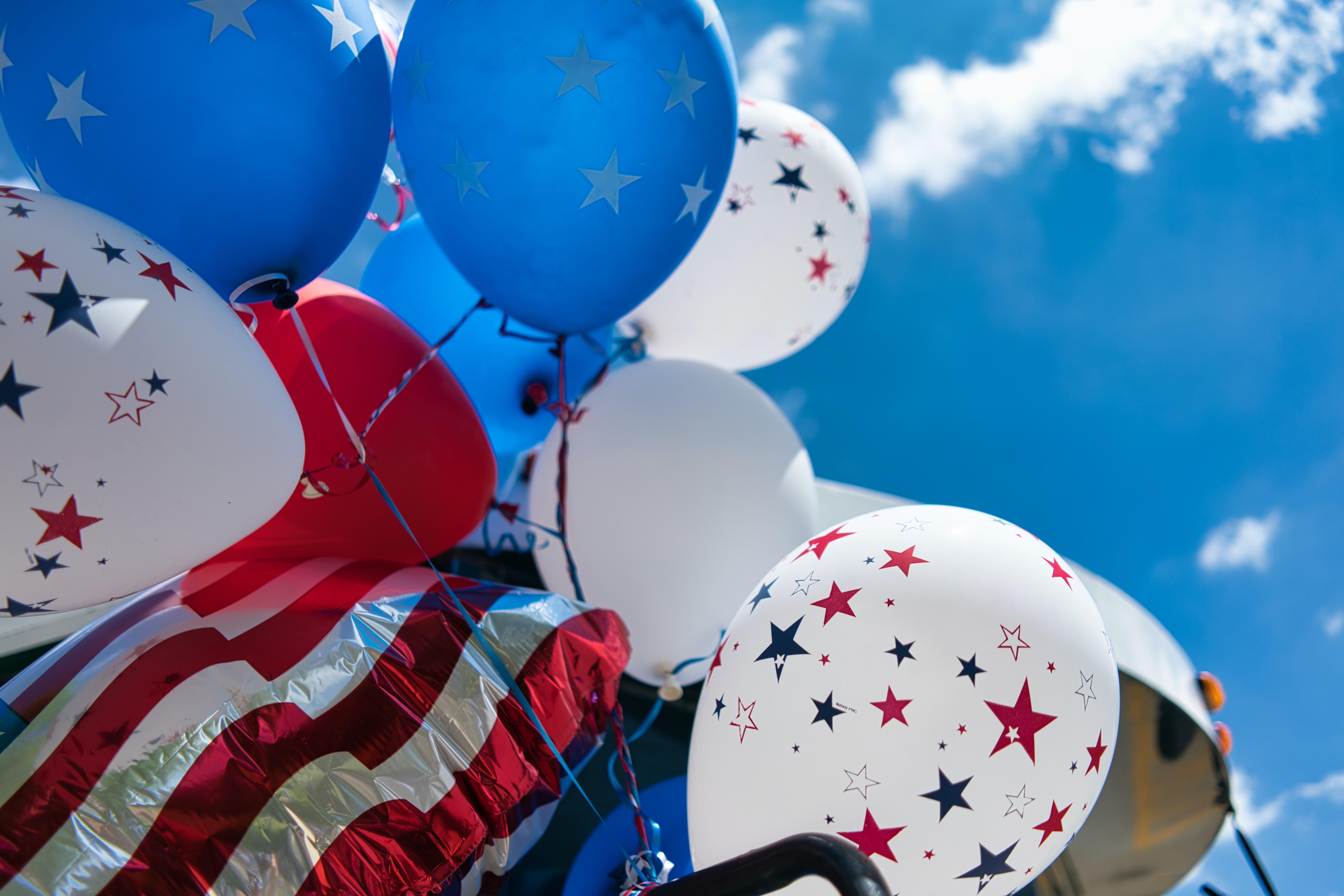 Red white and blue balloons with stars and stripes against a blue sky
