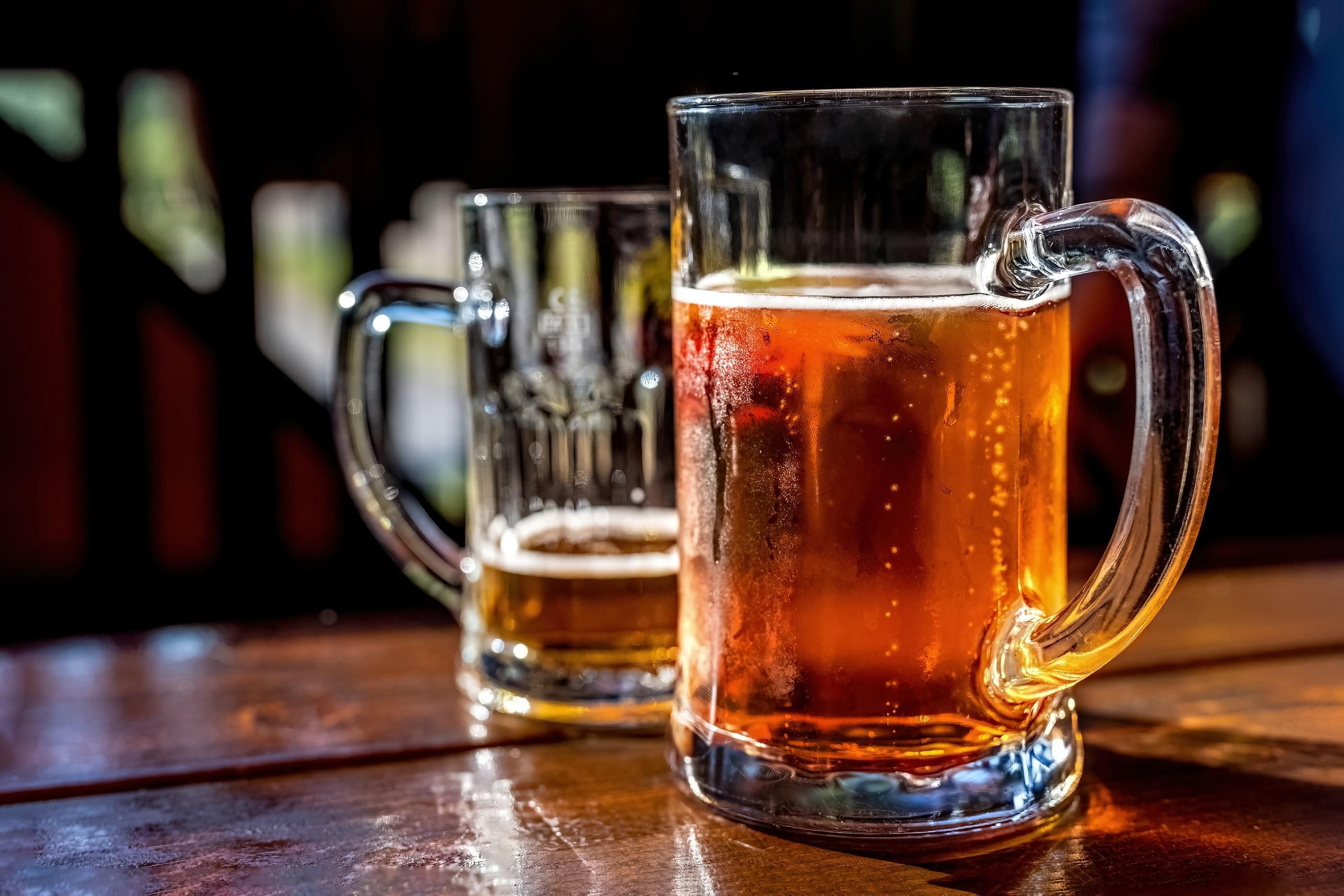 Two glass beer mugs on a wooden table
