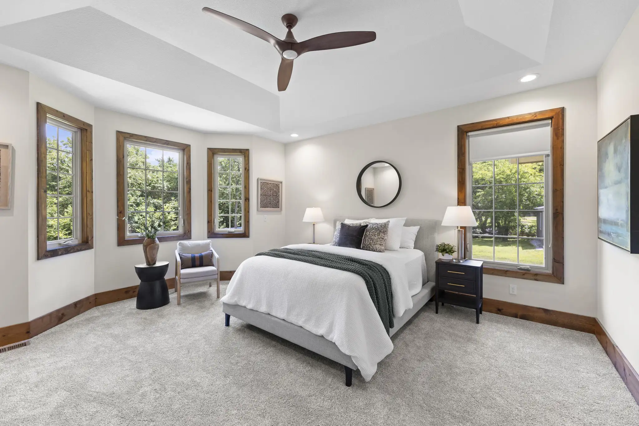 Main-level primary bedroom with bay windows and tray ceiling.