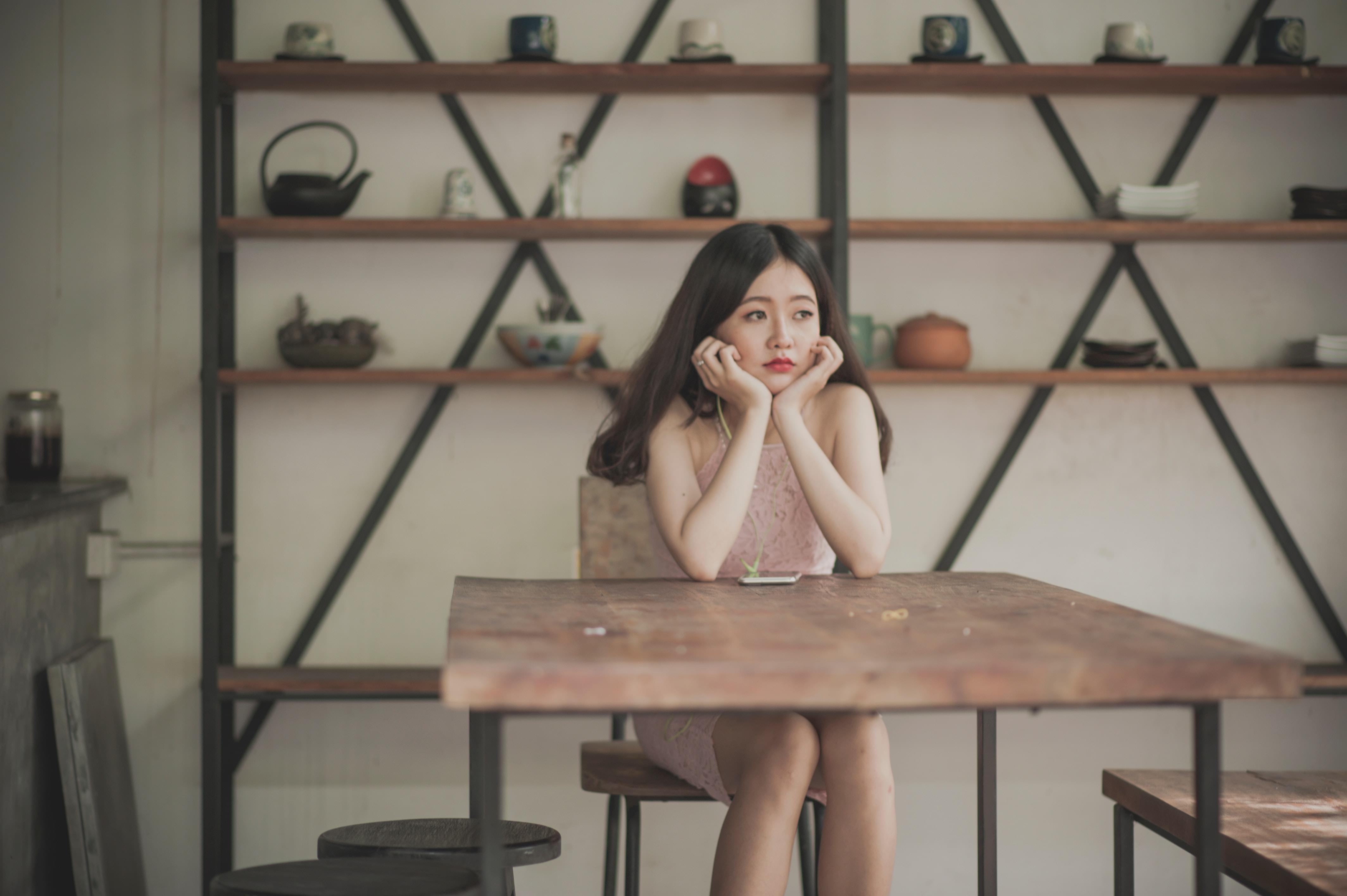 A young woman sitting at a table resting her chin in her hands