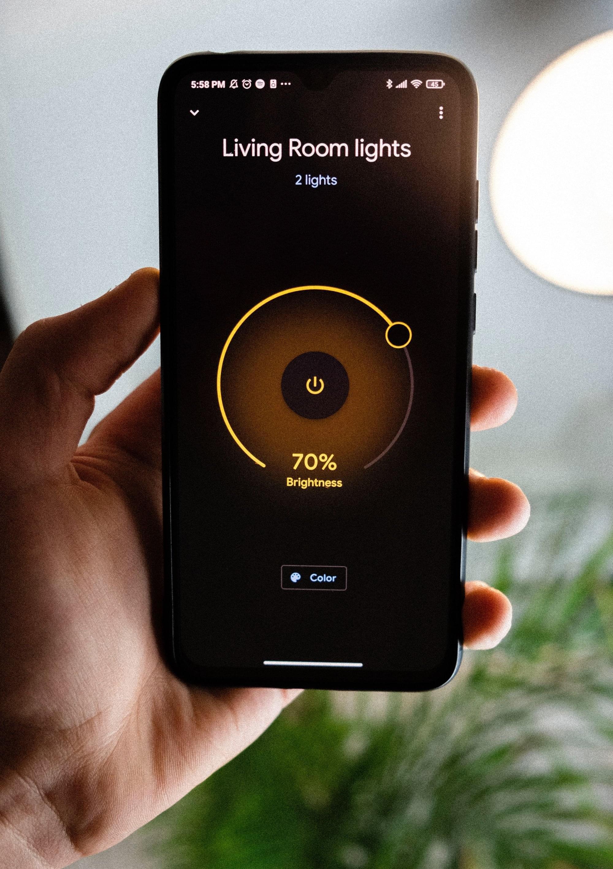 A smart phone with a screen showing control for the living room lights and their brightness