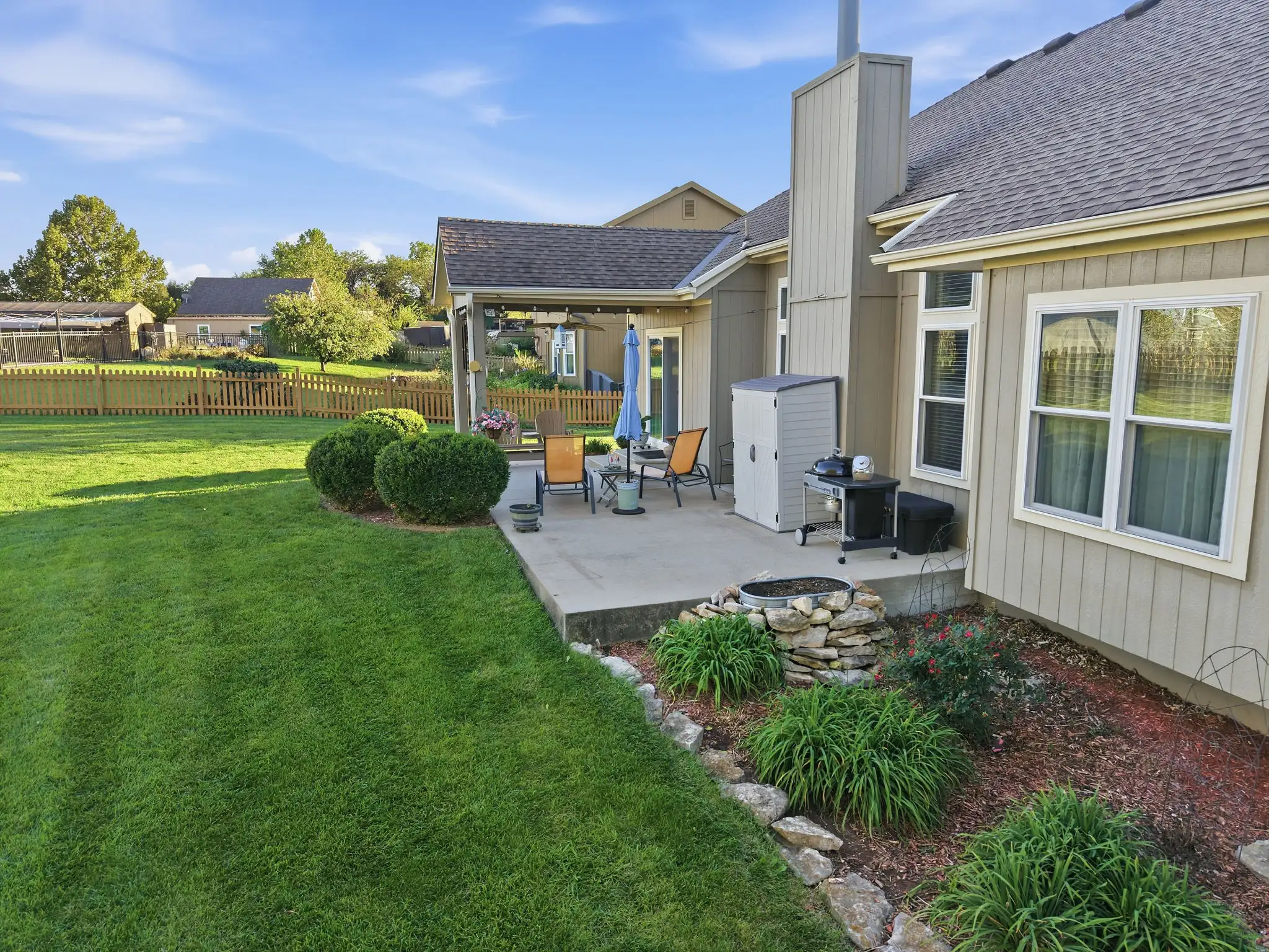 Back of the home with patio, grill area and landscaped beds