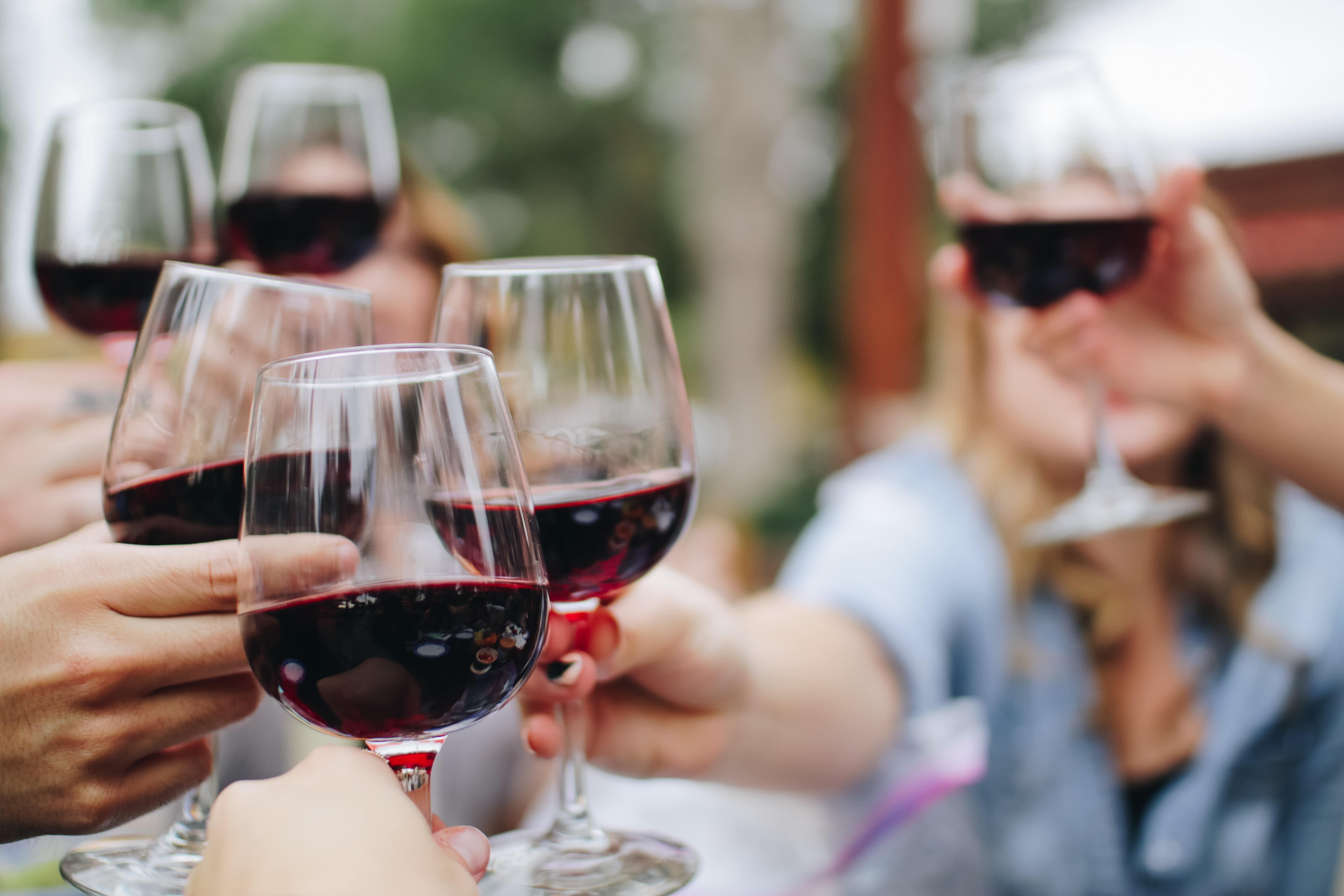 6 people holding glasses of red wine and toasting, selective focus