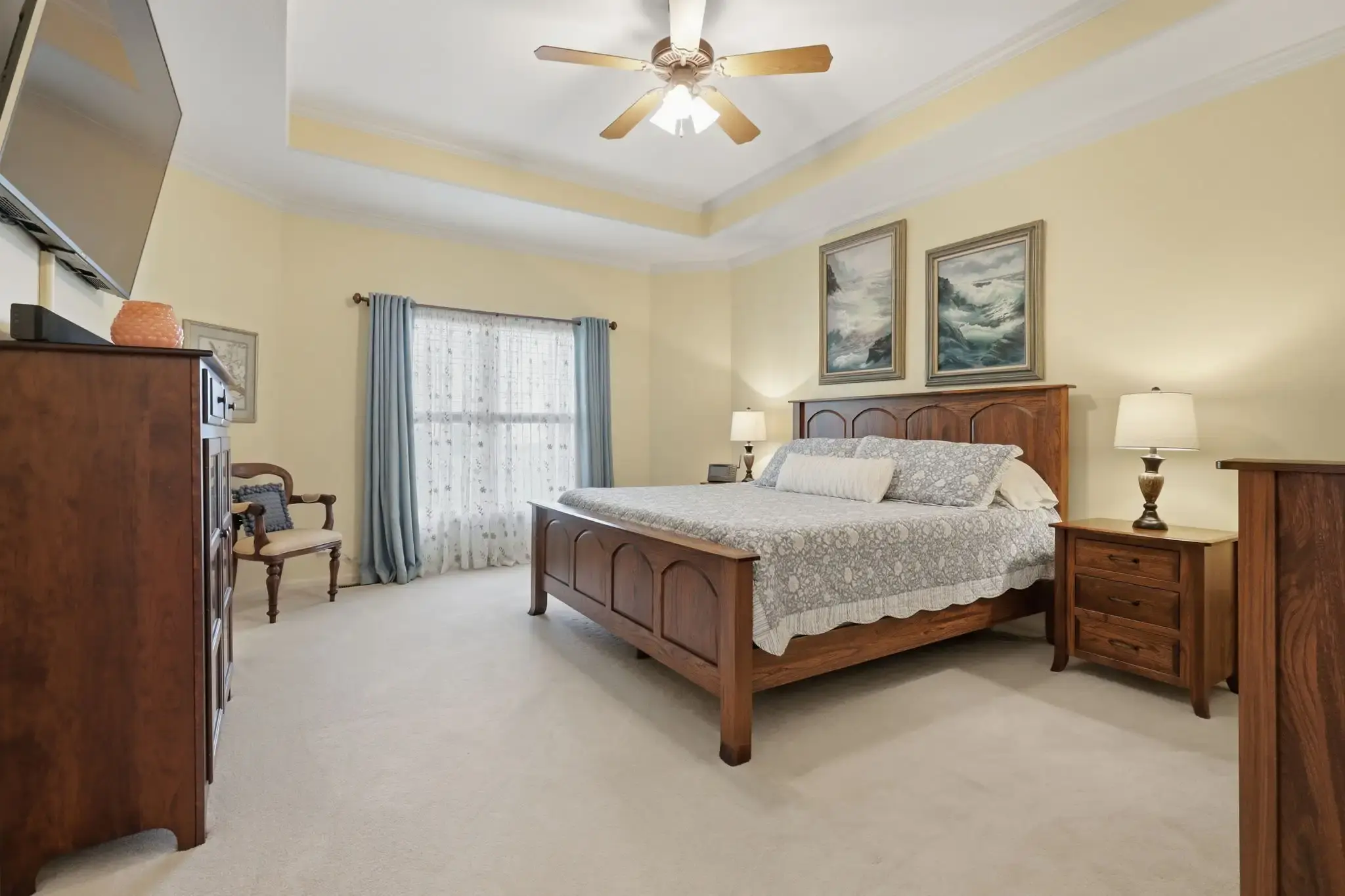 Primary bedroom with tray ceiling and ceiling fan