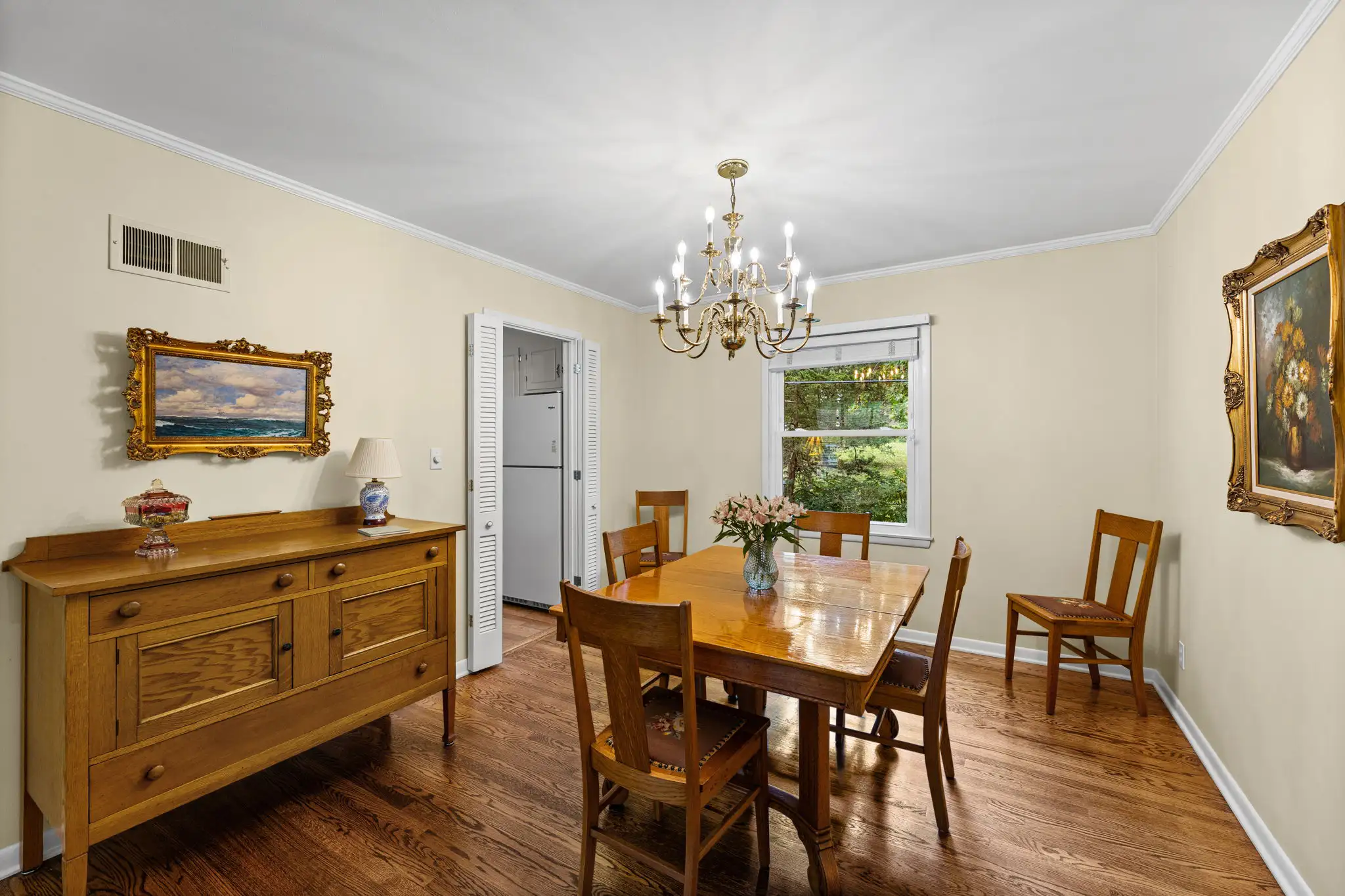 Formal dining room with hardwood floors, crown molding and a side window