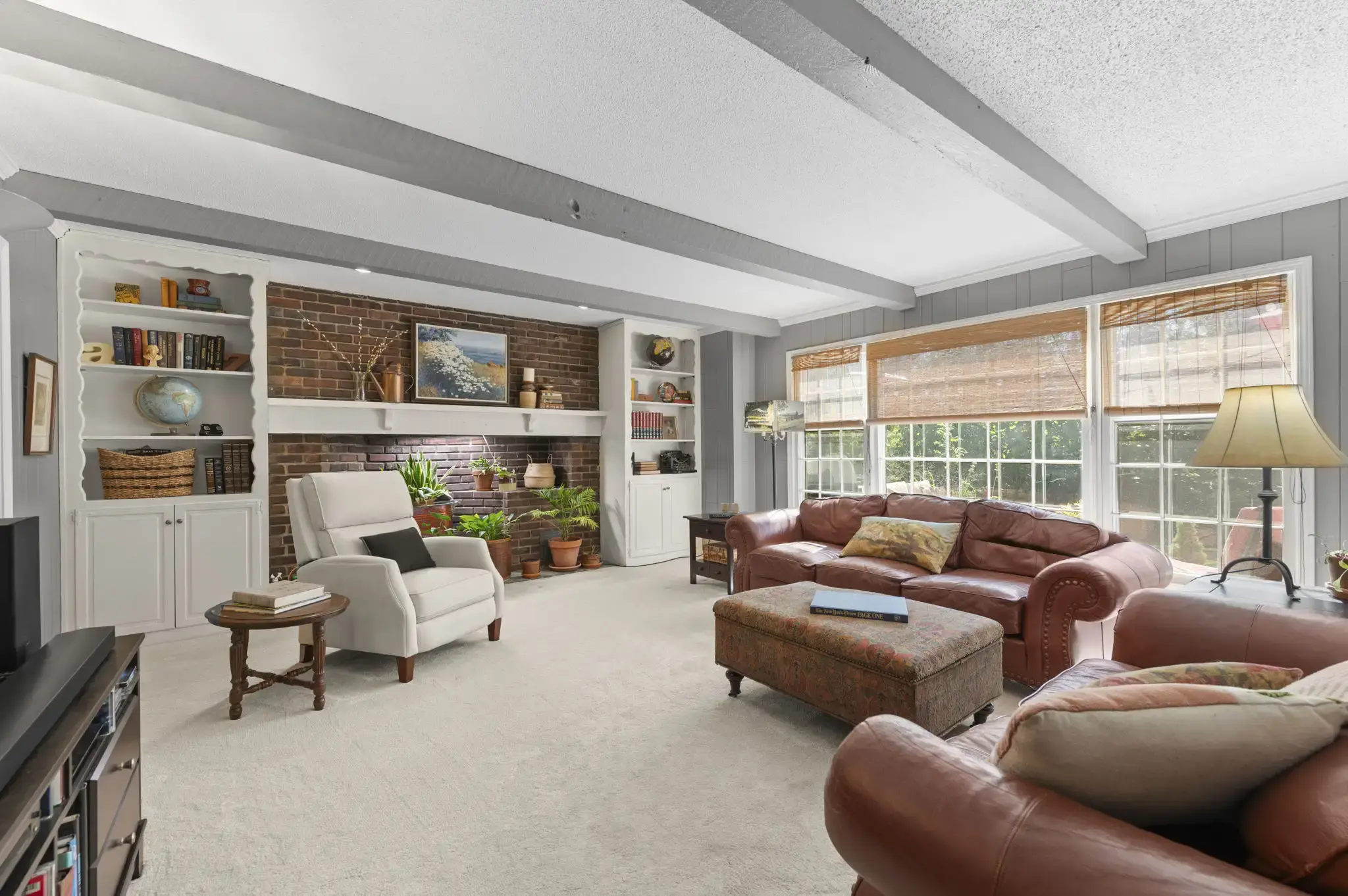 Family room with beamed ceiling and wall of windows overlooking the backyard