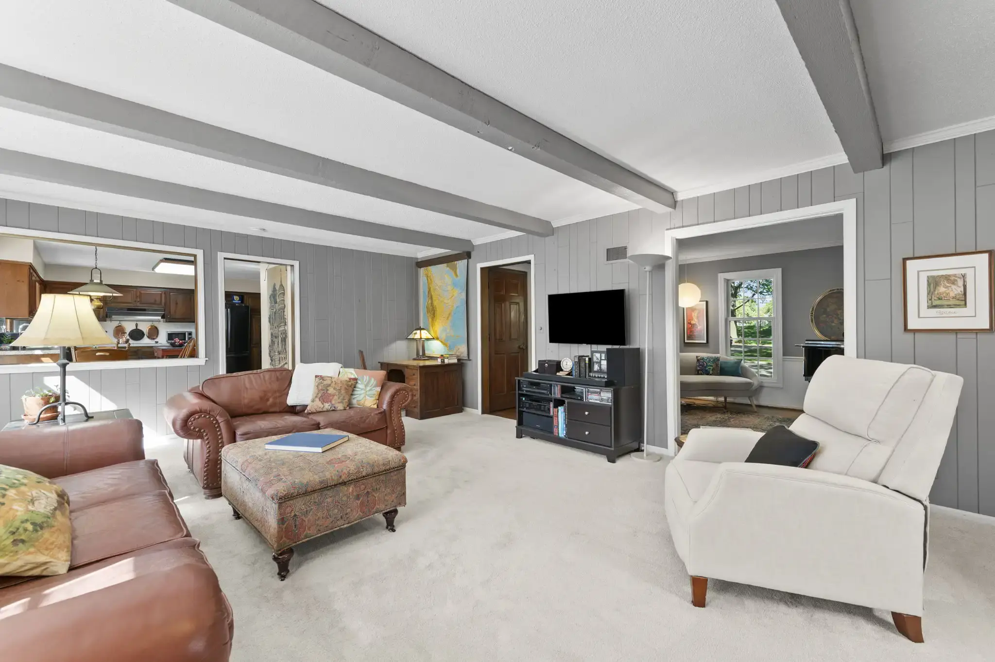 Family room with beamed ceiling, paneled walls and pass-through to the kitchen