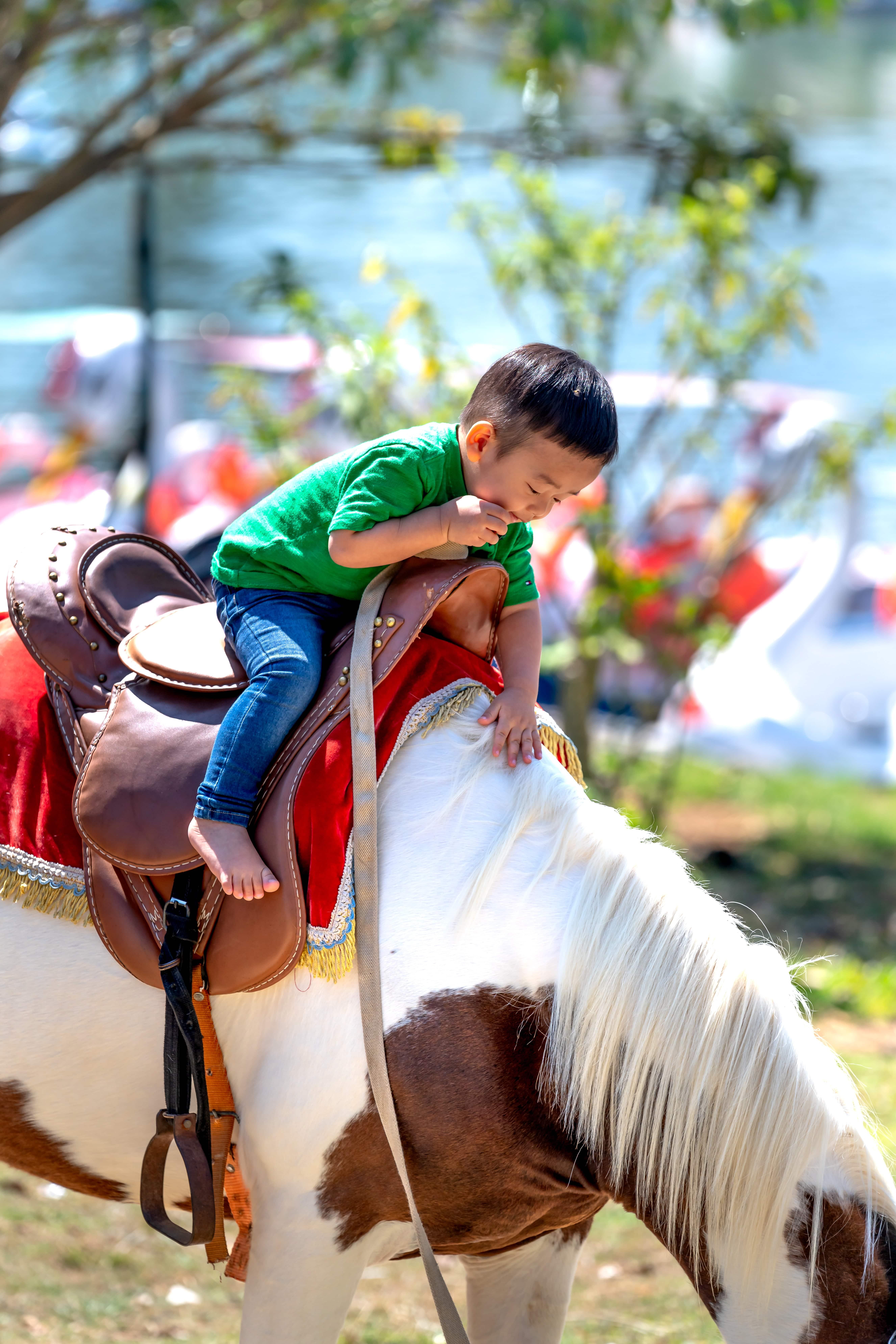 A small child riding a horse, leaning over to pet its neck