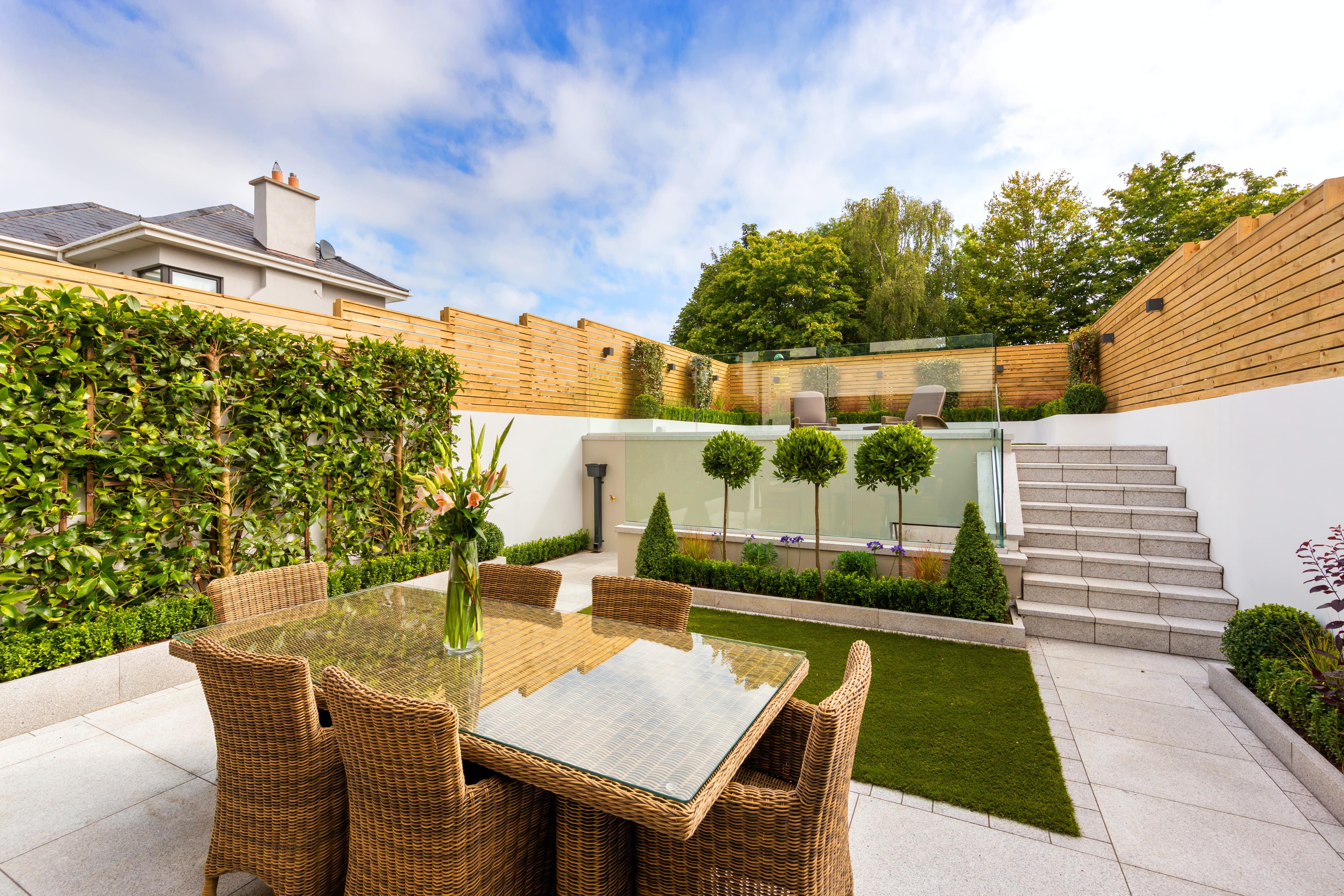 A luxury outdoor space with wicker furniture and green landscaping