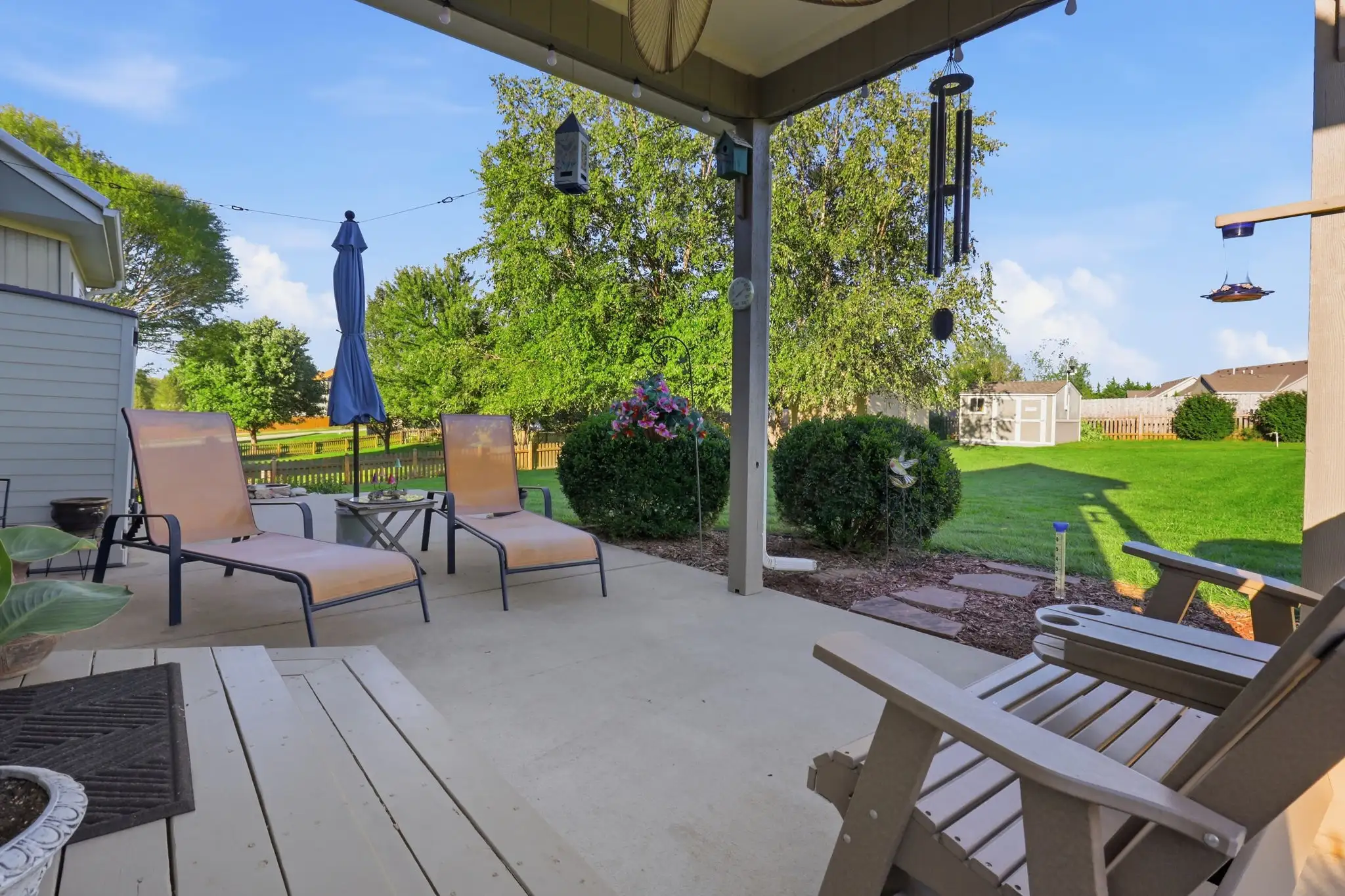 Covered patio overlooking the fenced backyard and mature trees