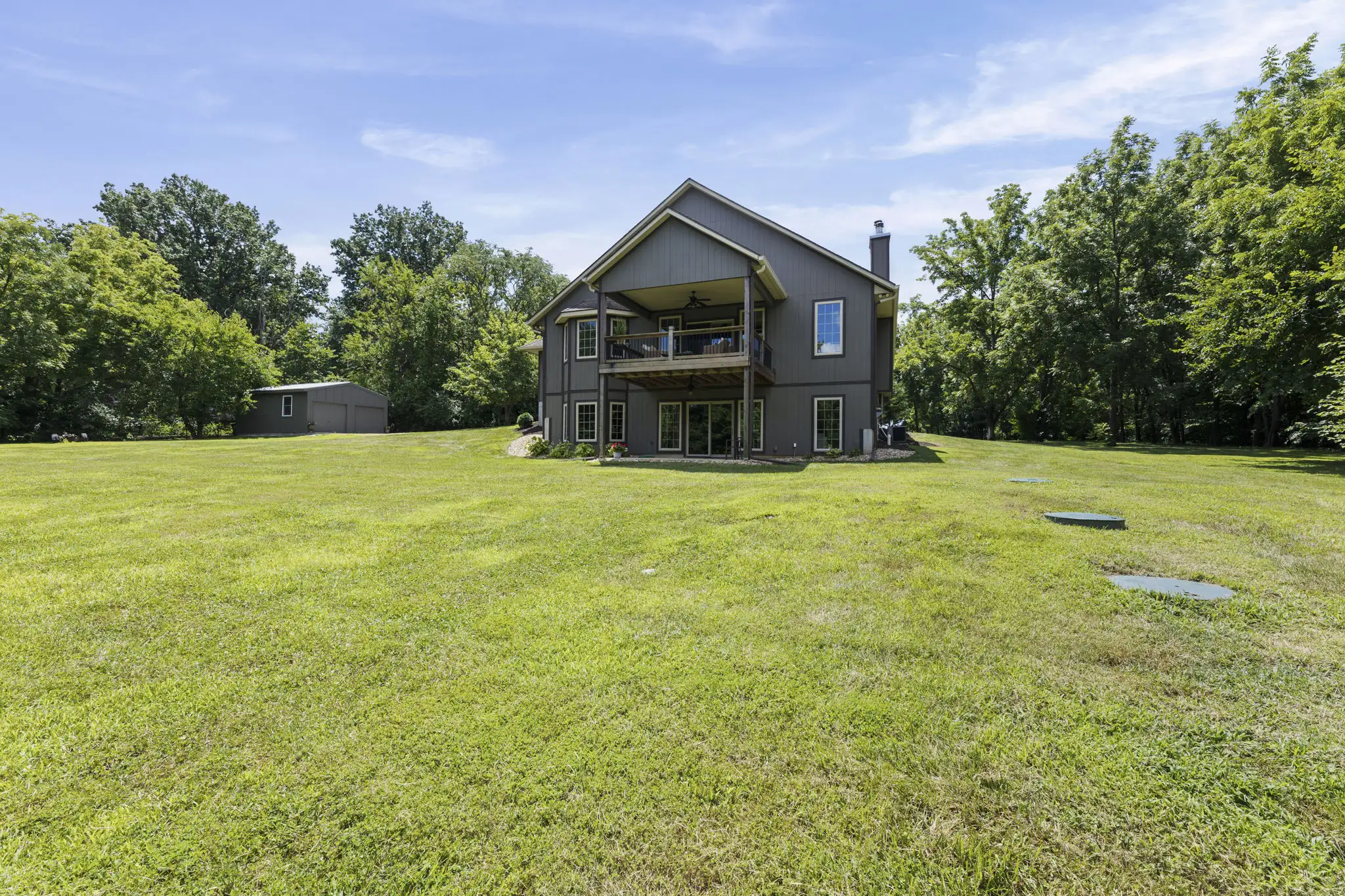 Back exterior with covered deck and walkout lower level patio.