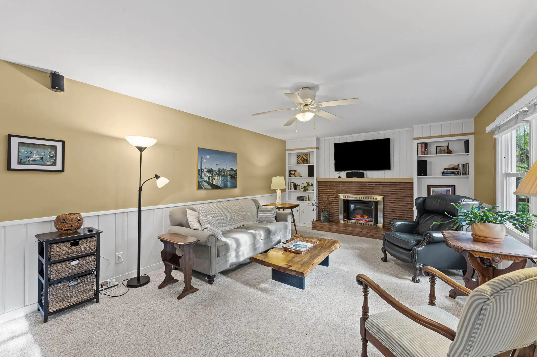 Family room with wainscoting, a brick fireplace and backyard windows