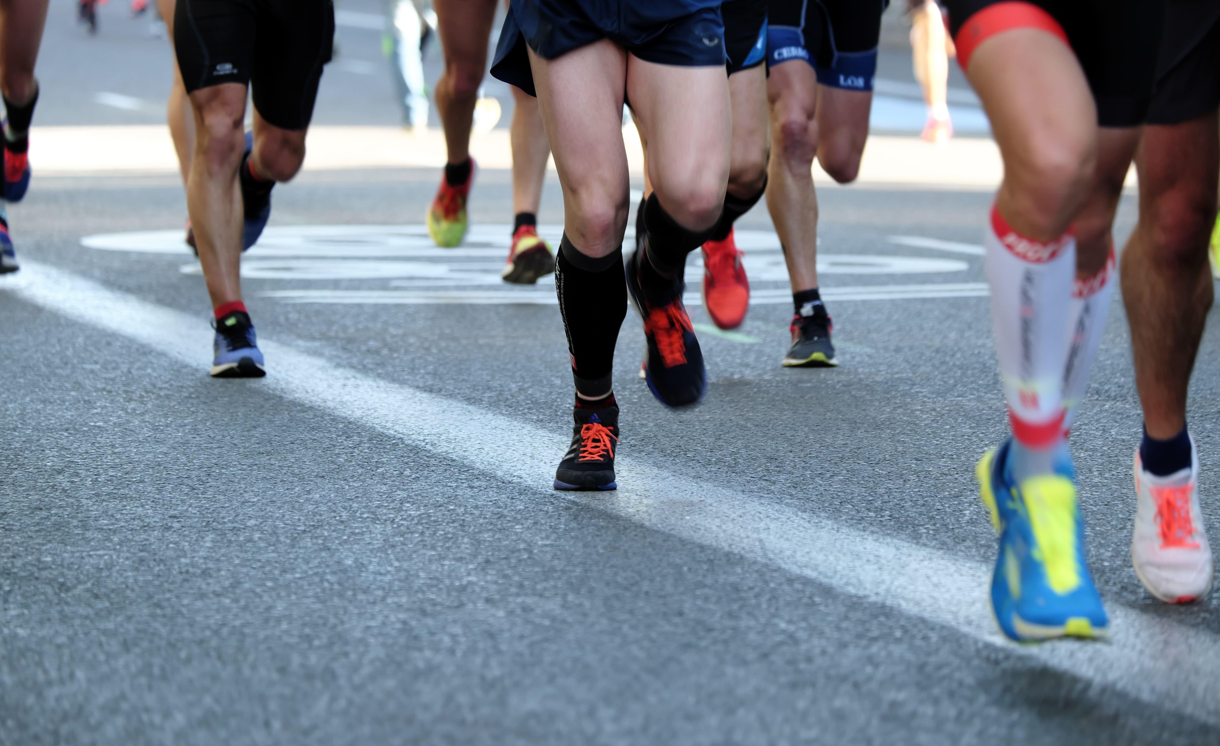 Runners from the knee down on an asphalt street