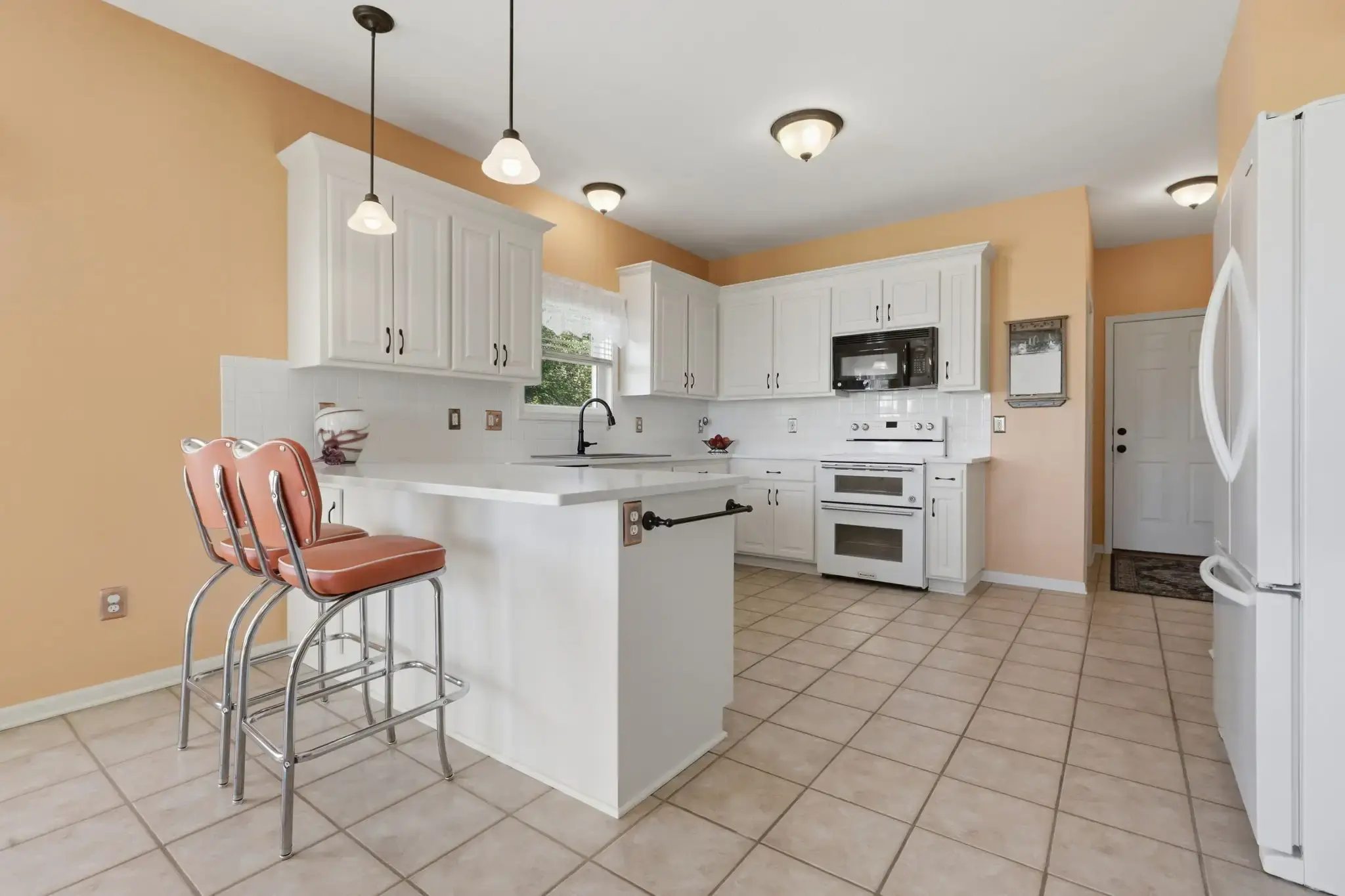 White kitchen with eating area, double oven and pendant lights