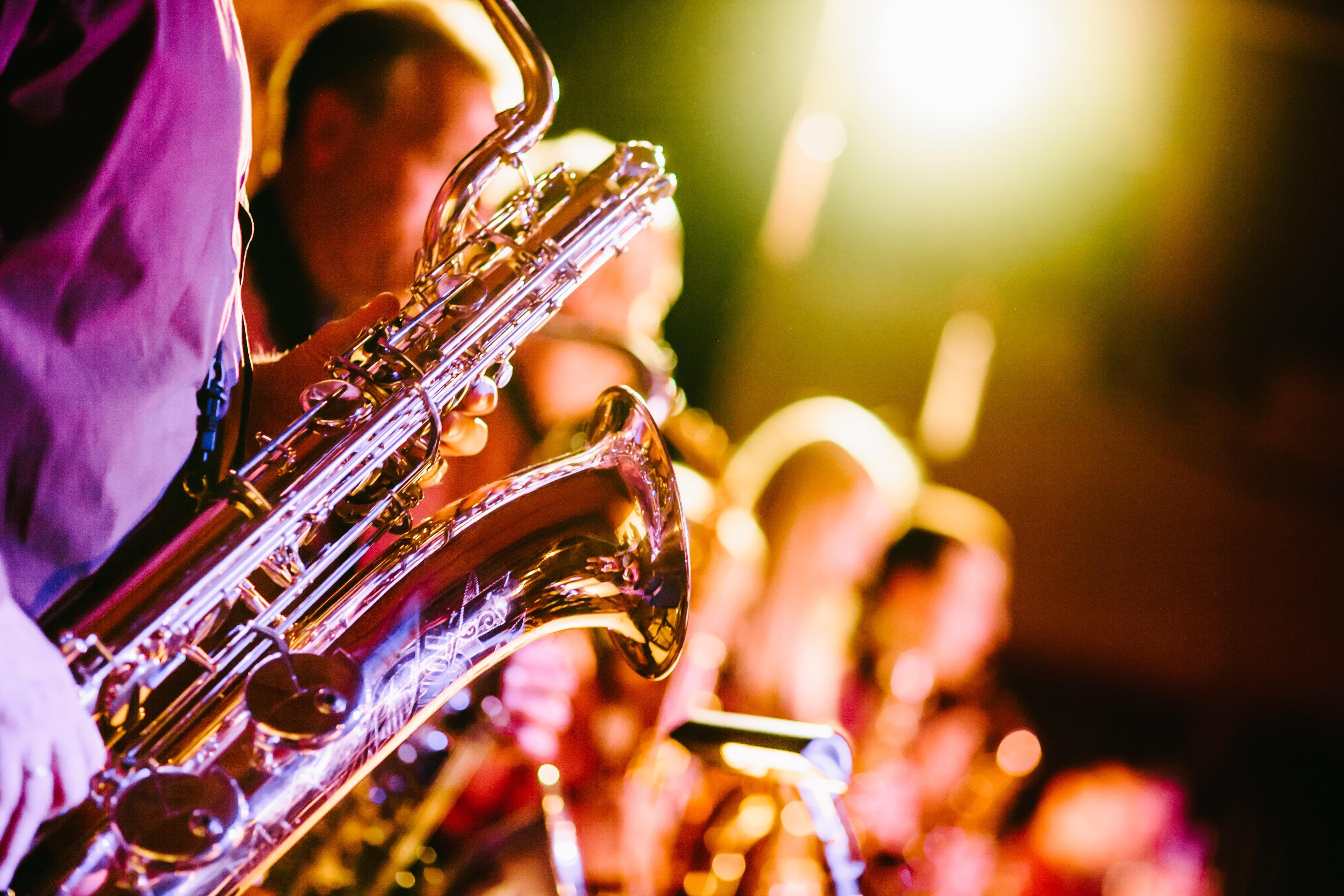 Colorful closeup on musicians playing brass instruments with a saxophone in focus