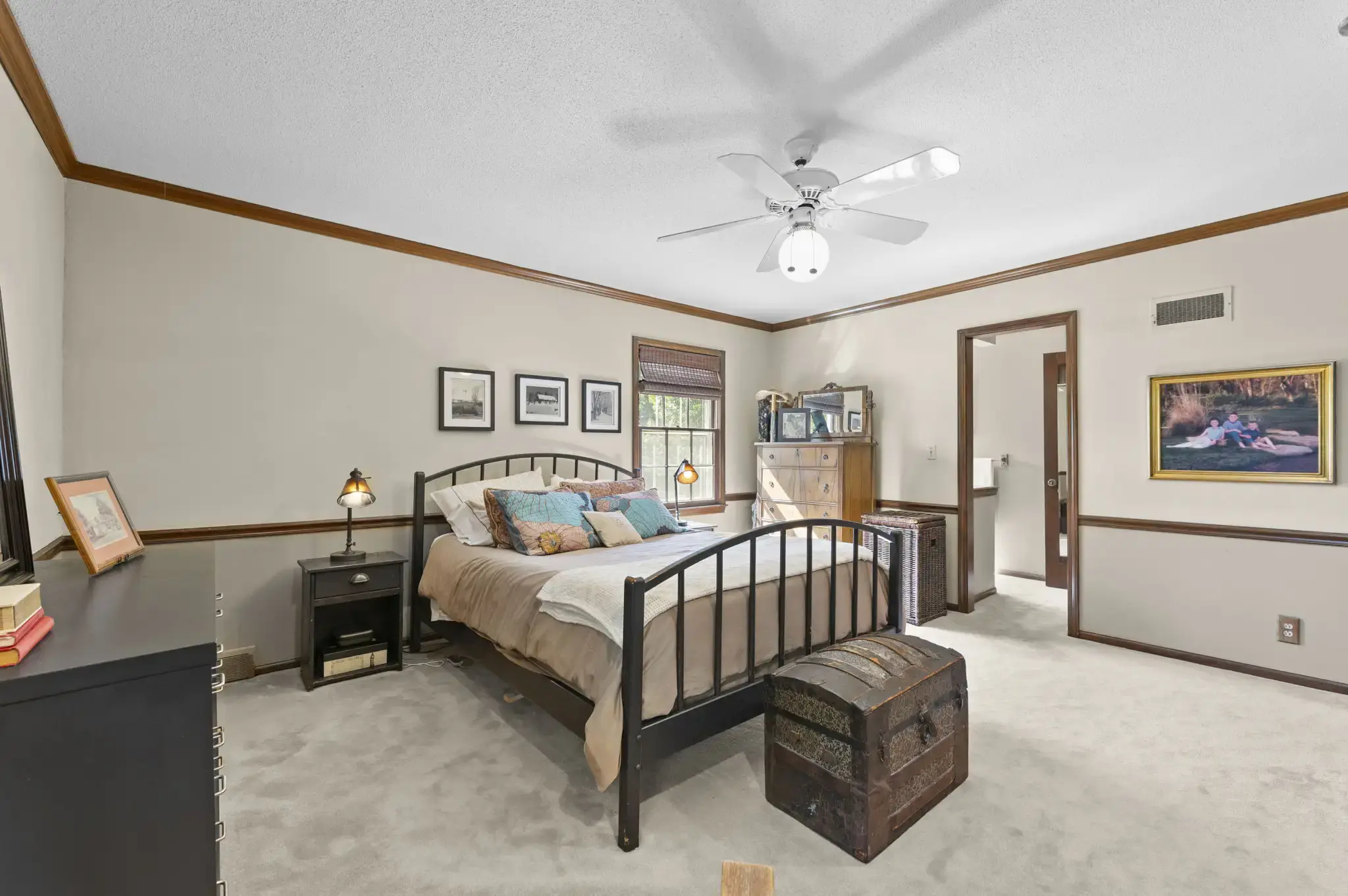 Primary bedroom with chair rail and doorway to the private bath