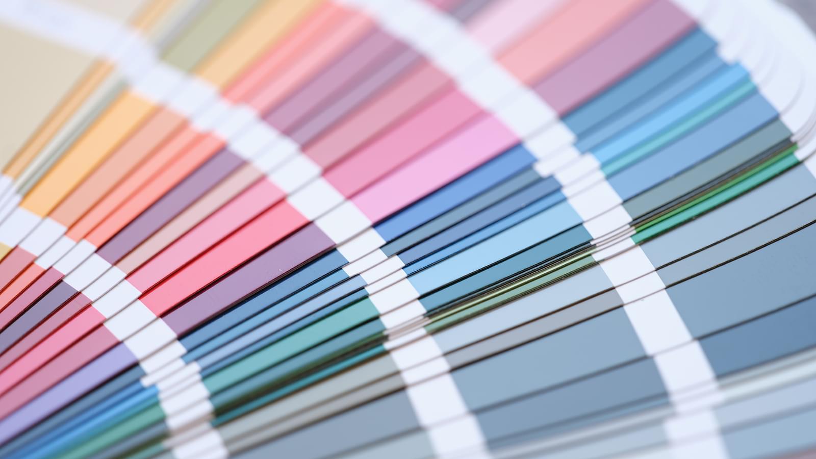 A closeup on paint chips ranging from yellows through pinks and blues into green