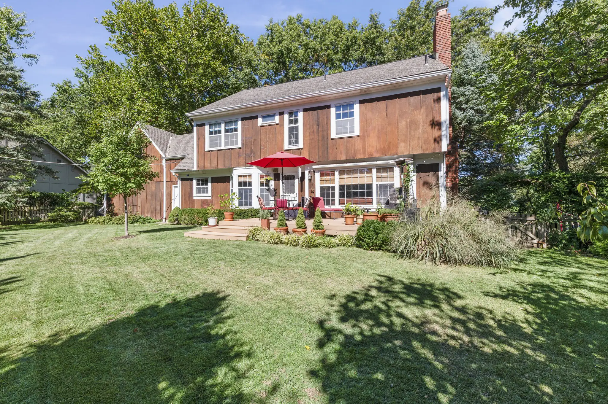 Rear of the two-story Colonial with deck and private backyard in Leawood, KS