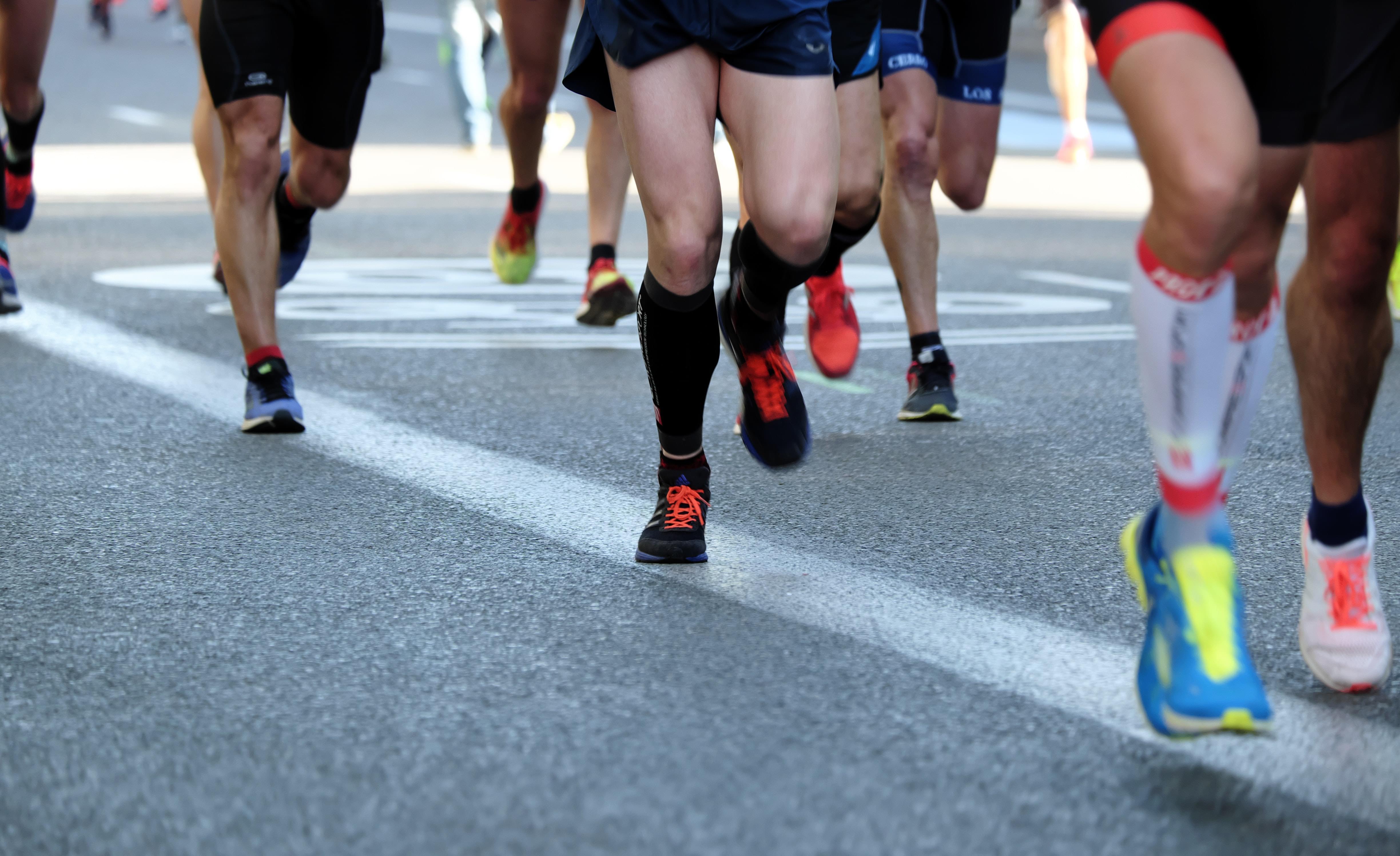 The legs of runners in a 5K race with colorful sneakers