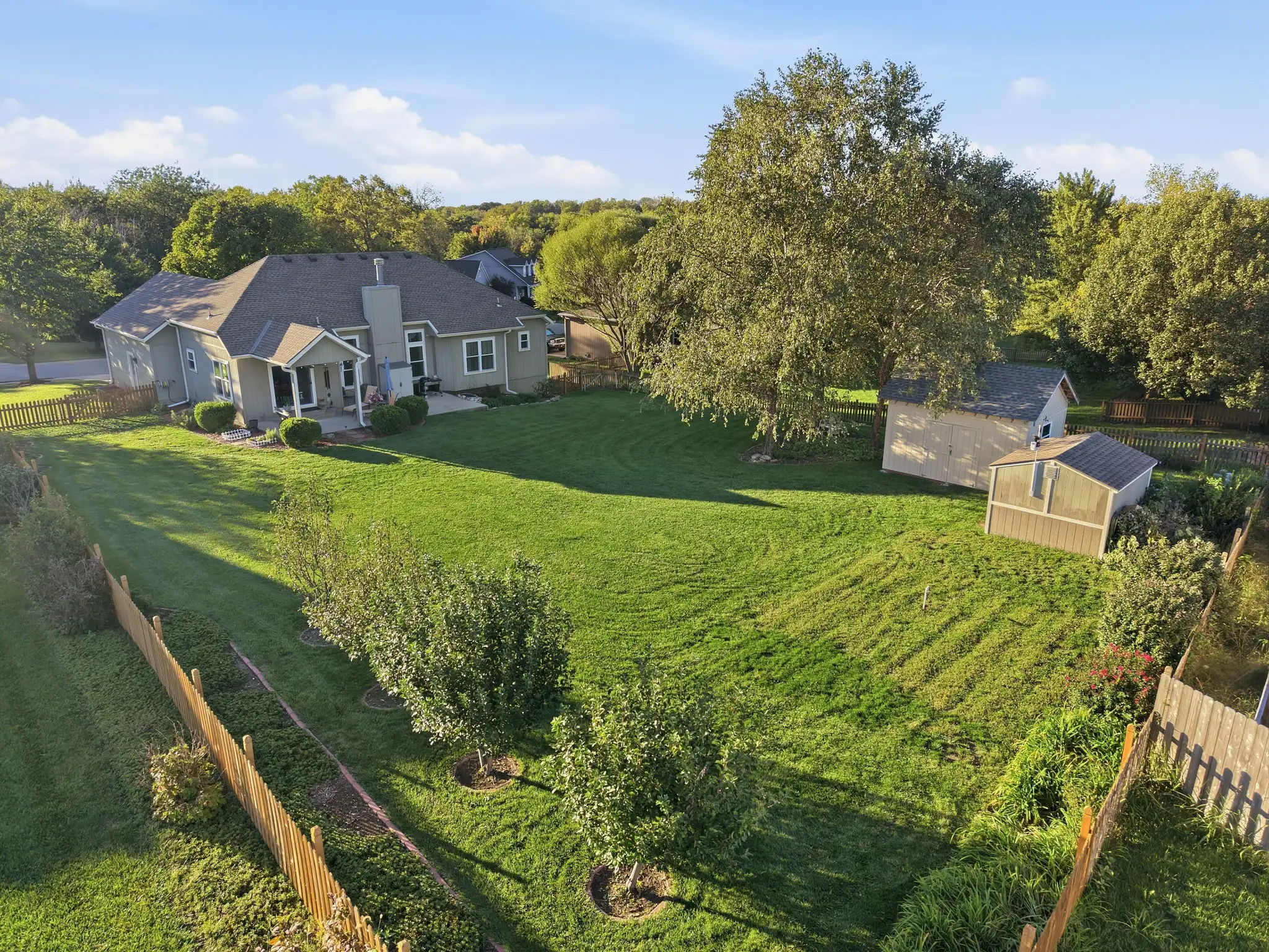 Aerial view of fenced half-acre backyard with fruit trees, two sheds and covered patio in the Timber Trails subdivision