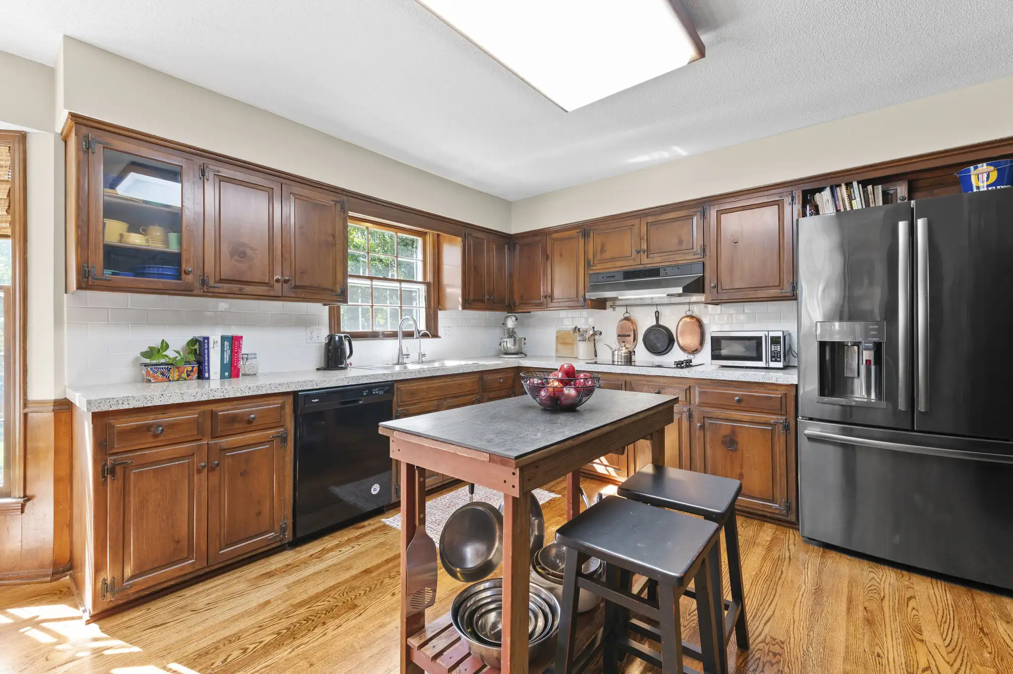 Kitchen with wood cabinetry, white subway tile backsplash and stainless refrigerator