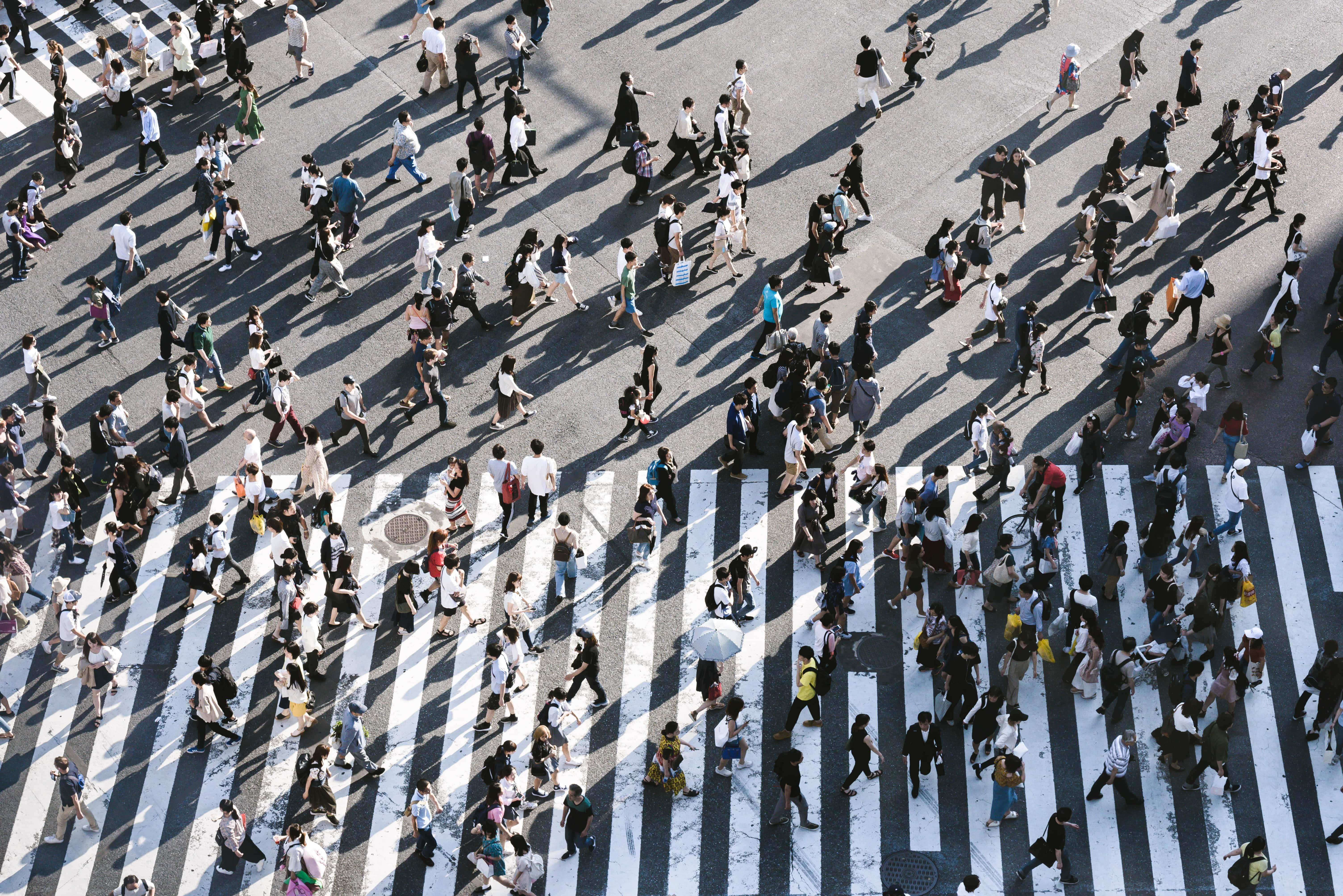 Many people crossing a cross walk