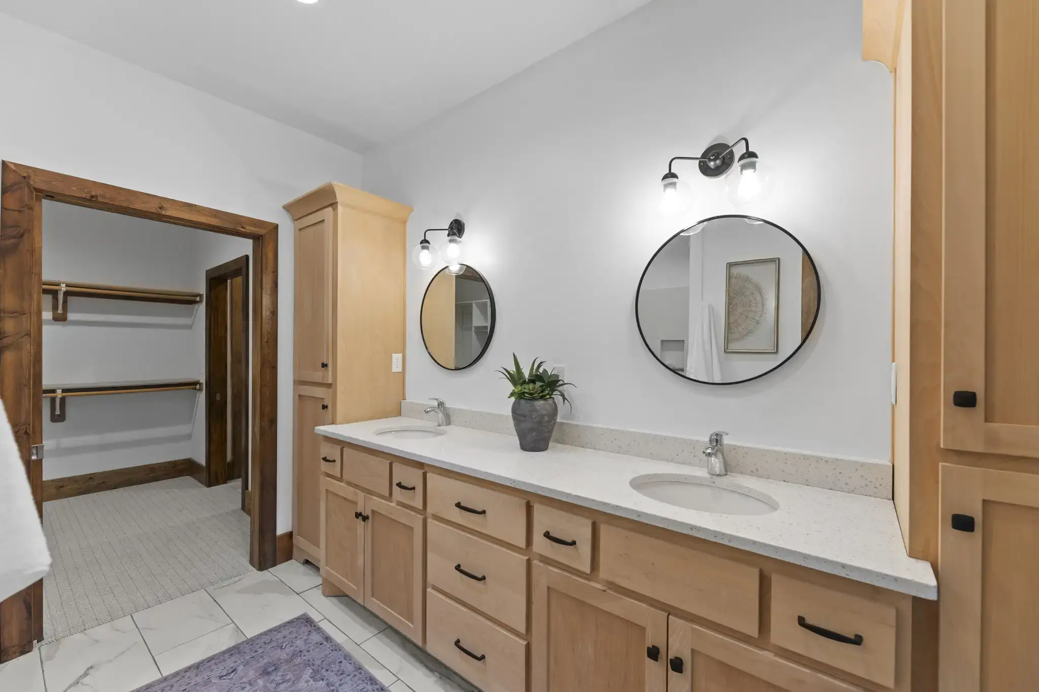 Primary bathroom with dual vanities and walk-in closet access.