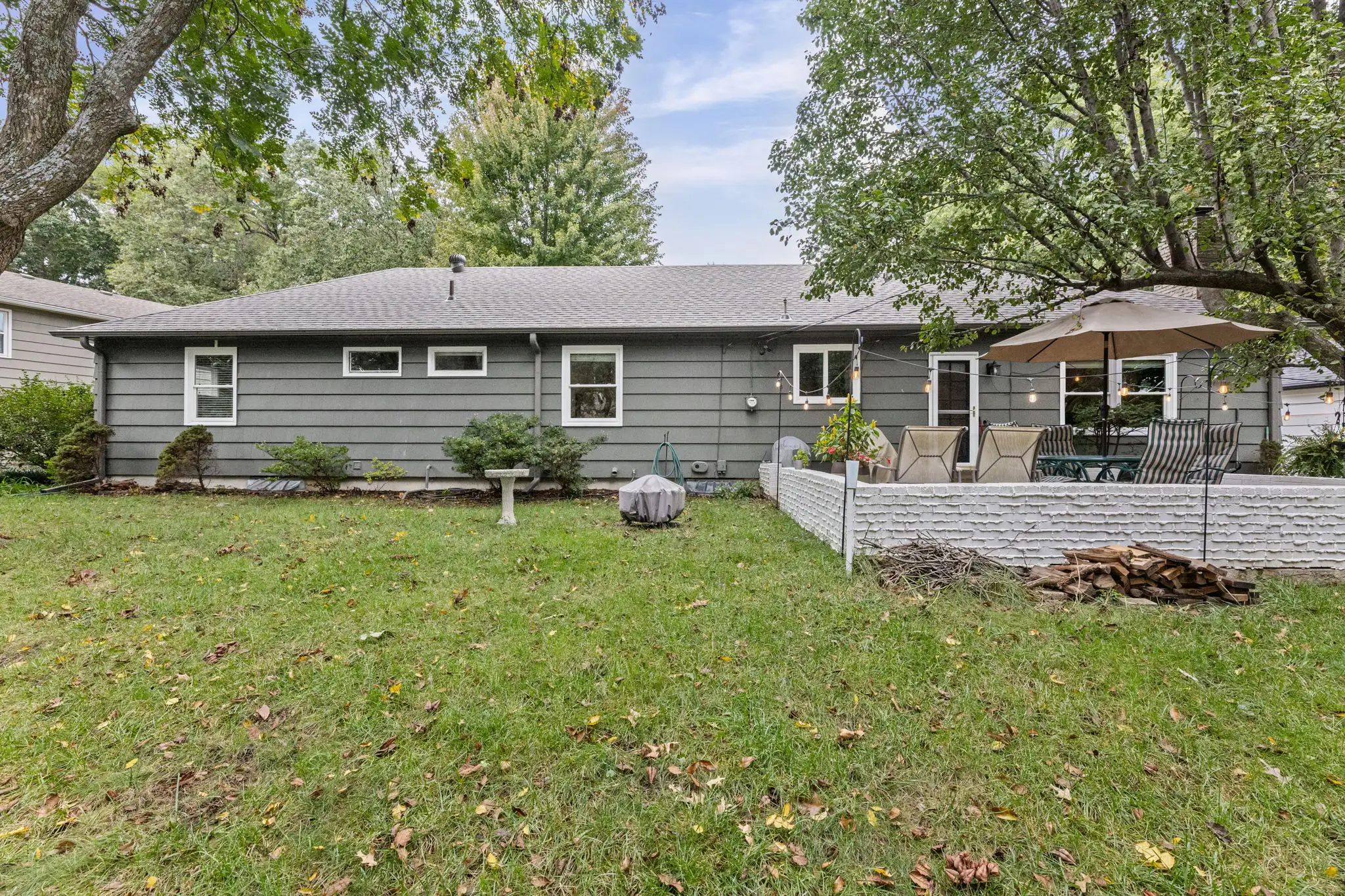 Back of a Mission, KS ranch with a brick-walled paver patio and a large lawn
