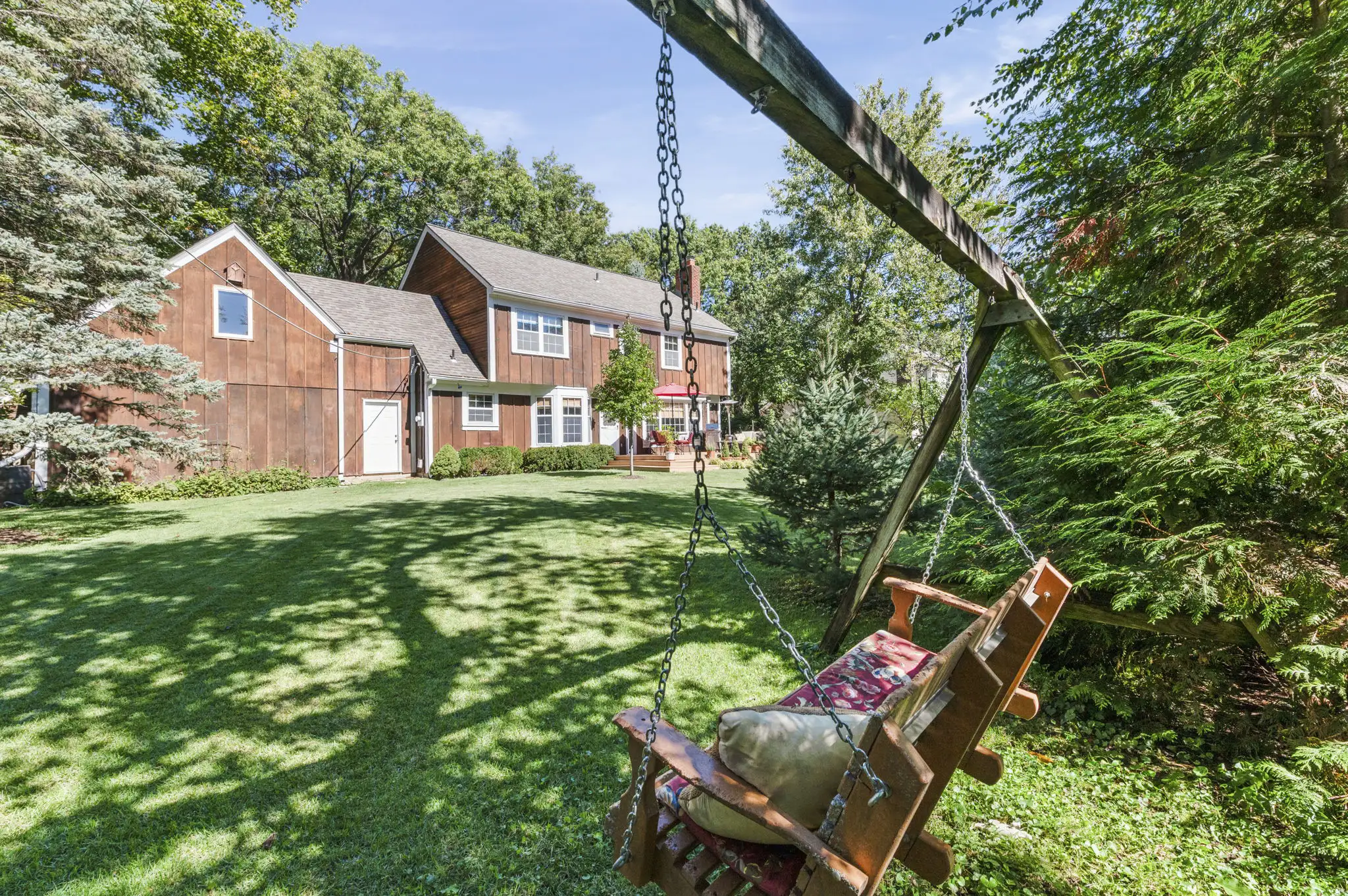 Shaded backyard lawn with evergreens and rear view of the home