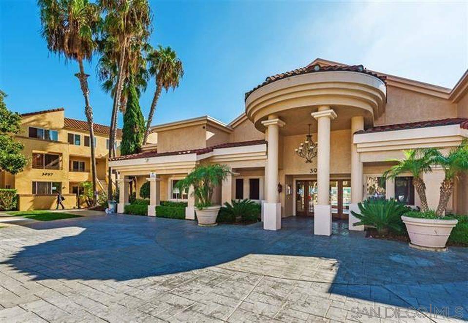 The entrance to a condo community with columns, palm trees, and a stone walkway