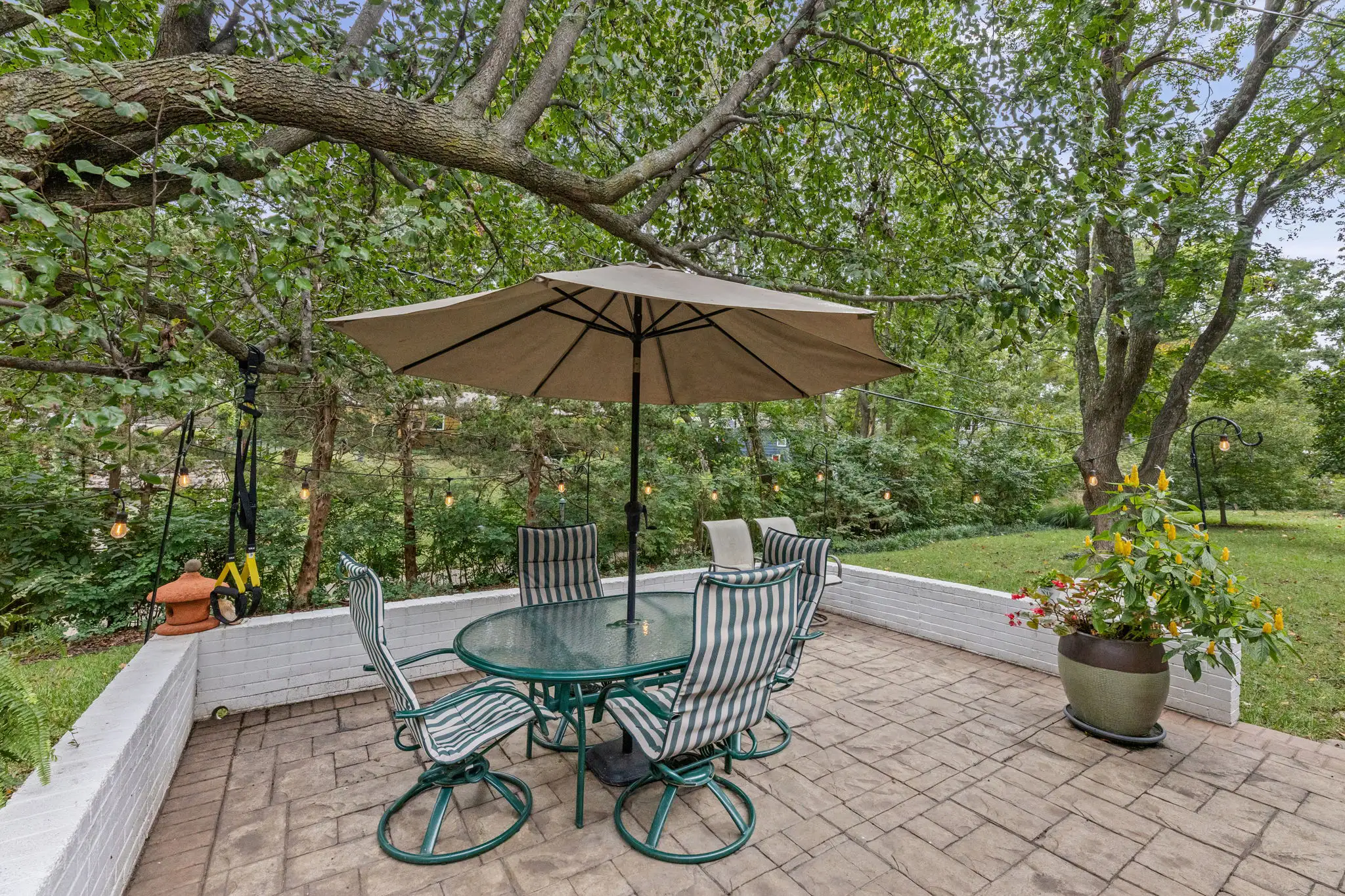 Paver patio with an umbrella table under mature trees