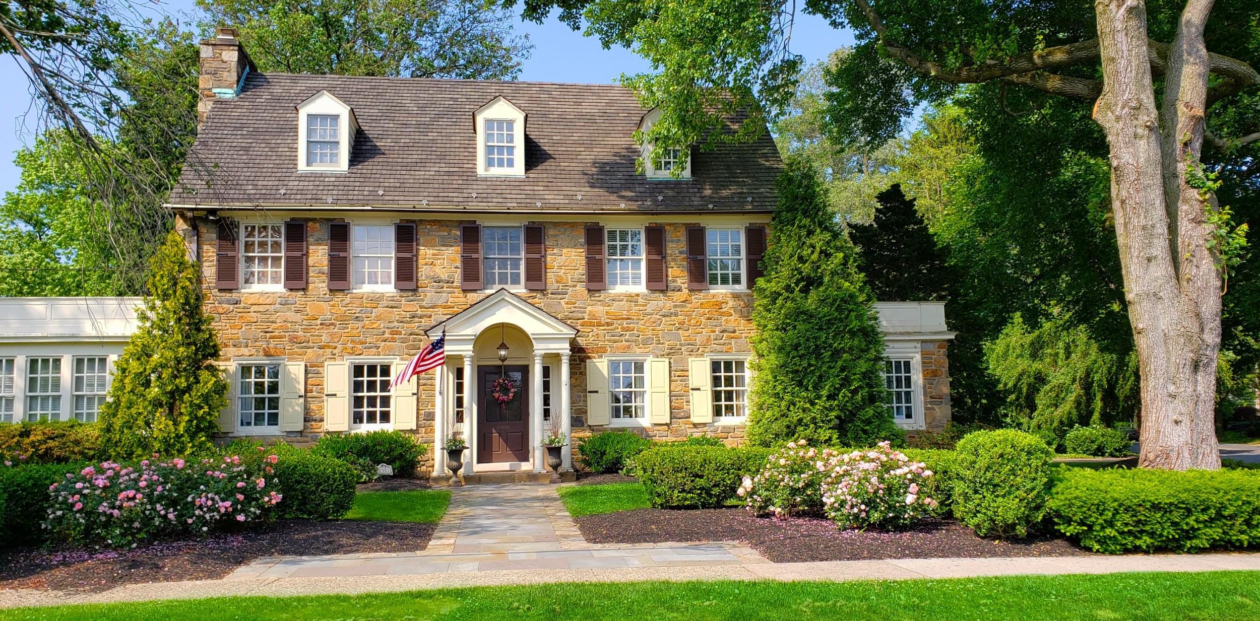 A stone facade house with a well-landscaped front yard