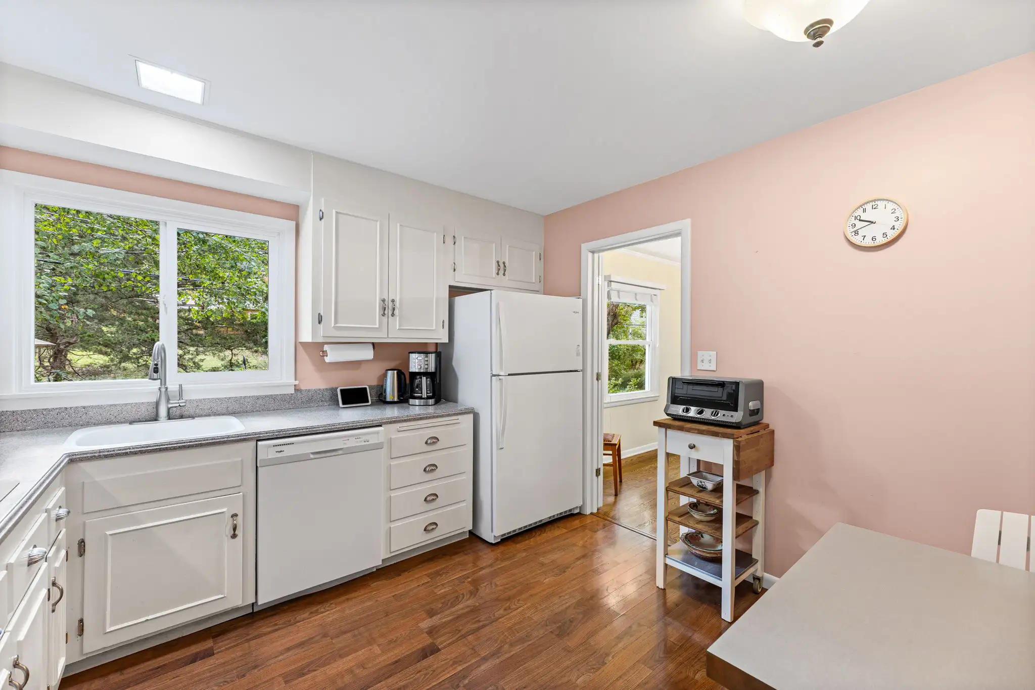 White kitchen cabinets with a microwave, wall oven and a window over the sink