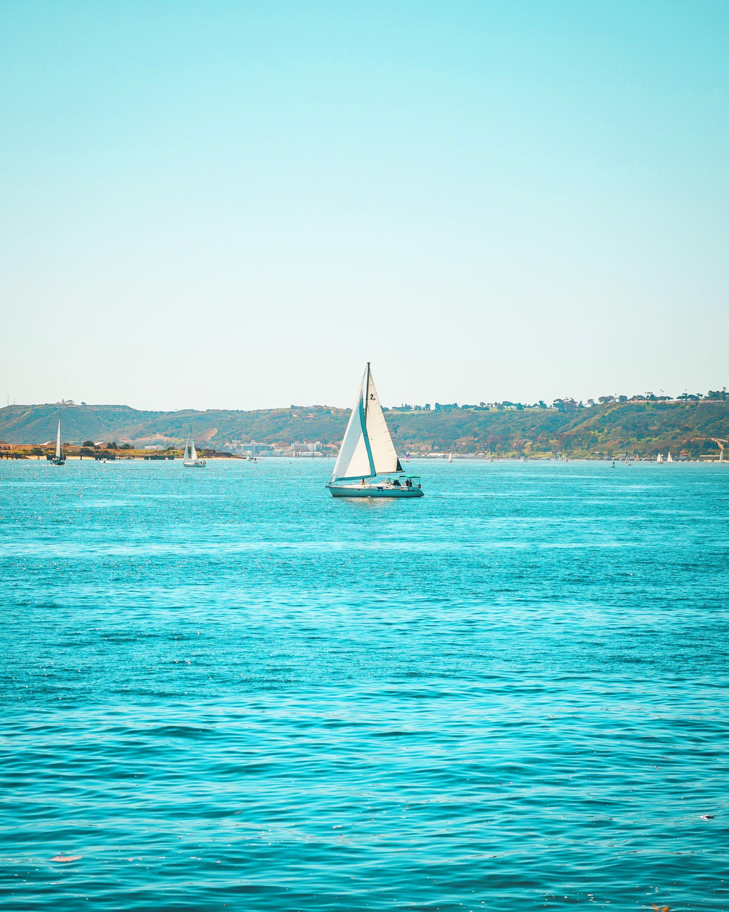 A sailboat on light blue water in the bay