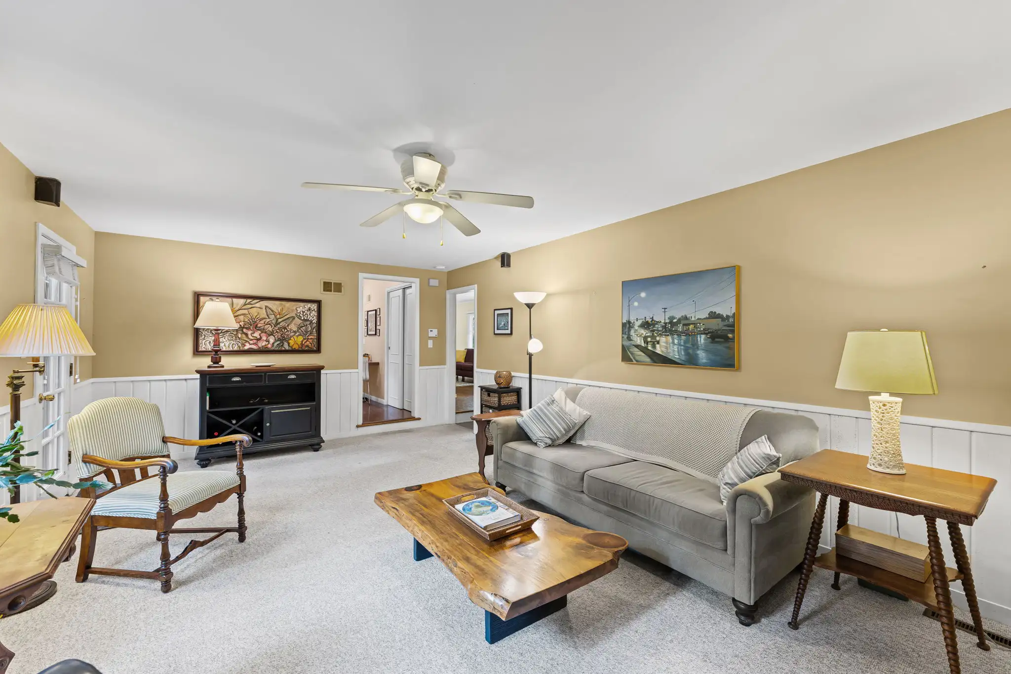 Family room with wainscoting and a ceiling fan, looking toward the hall