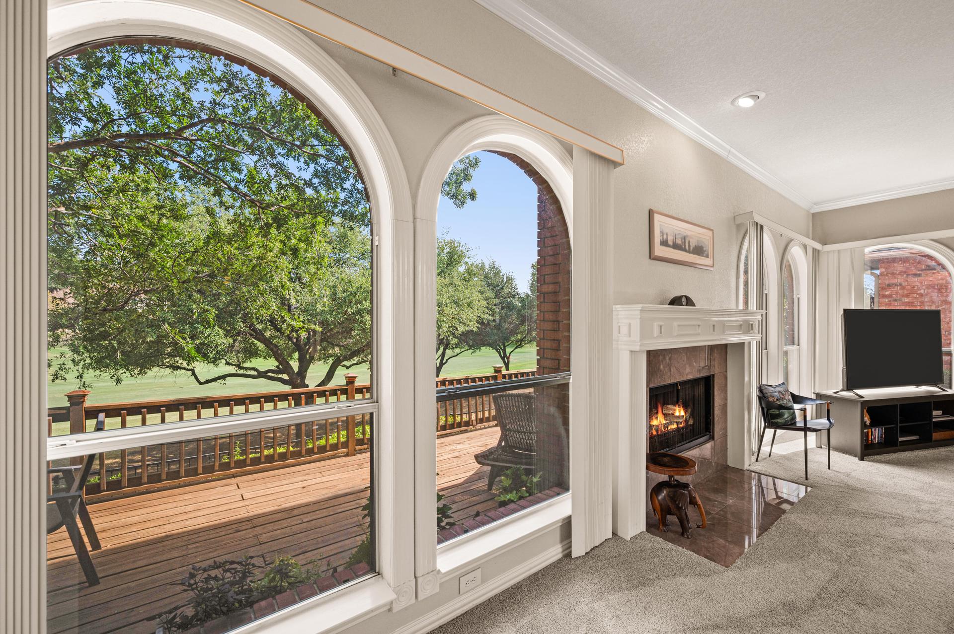 Living room with fireplace and arched windows overlooking the deck at 7626 Lakecrest Circle
