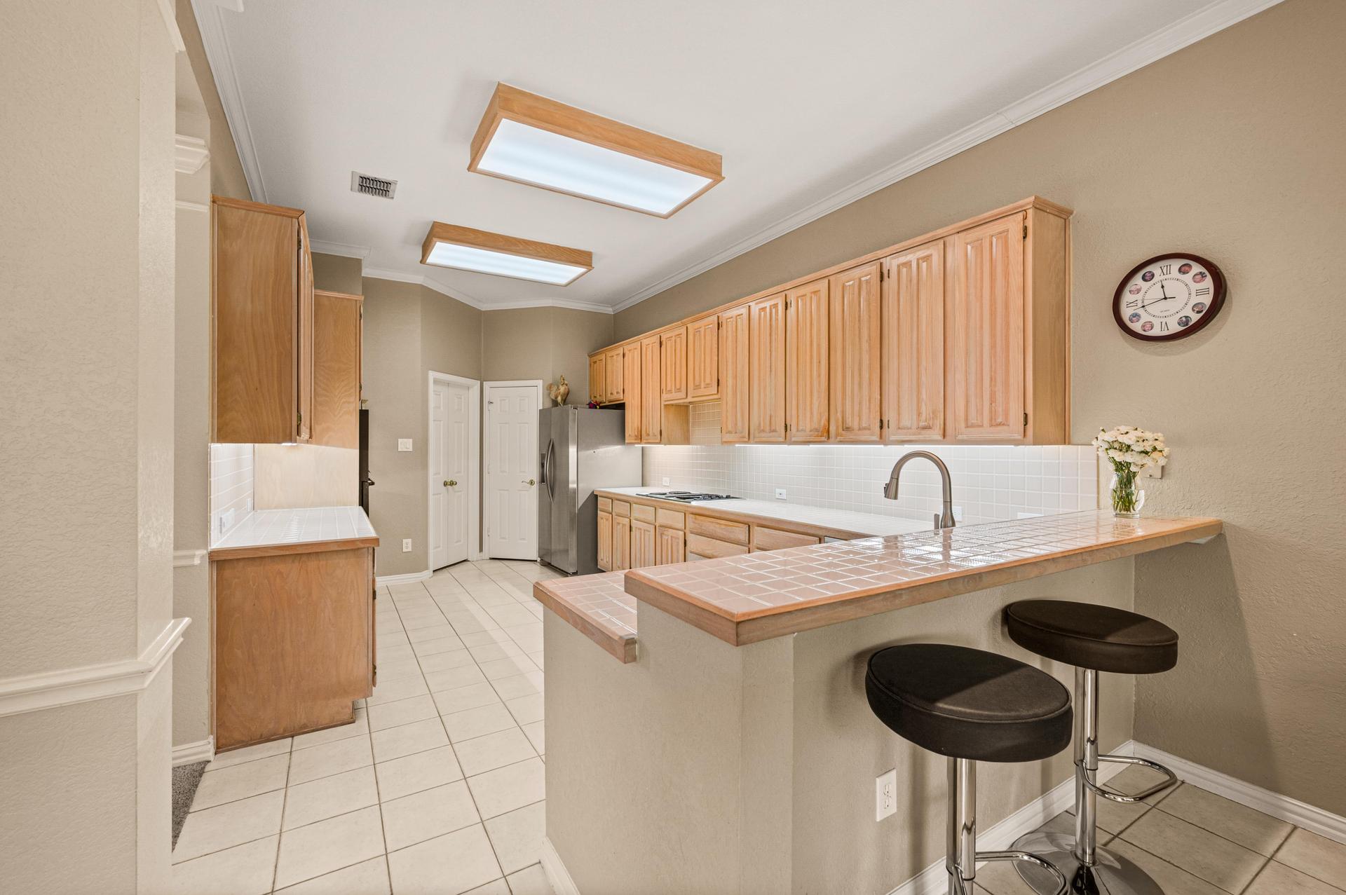 Kitchen with cabinetry, tile counters, island, and breakfast bar at 7626 Lakecrest Circle