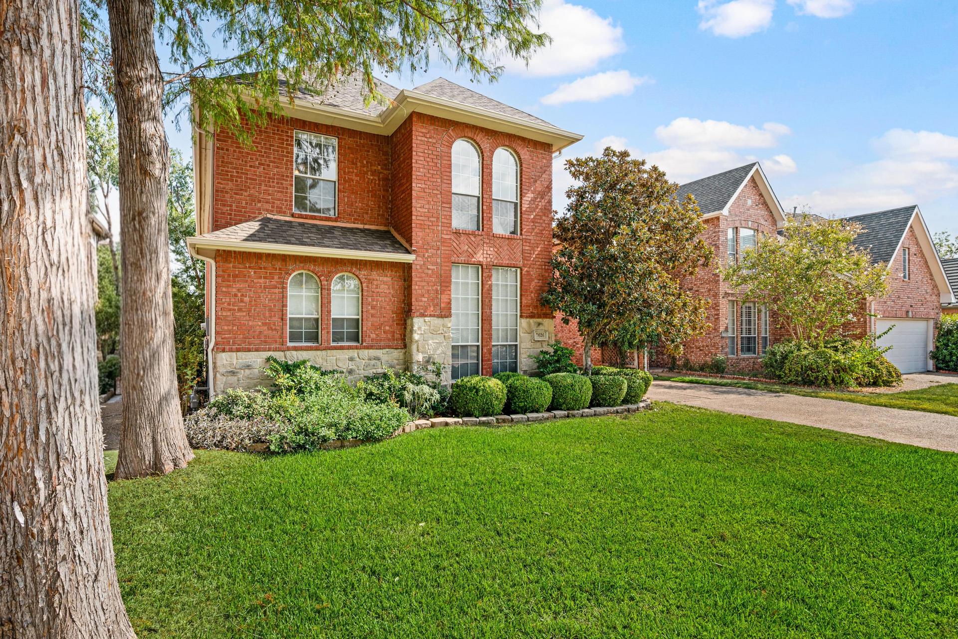 Front and side exterior of 7626 Lakecrest Circle with brick facade and landscaped grounds