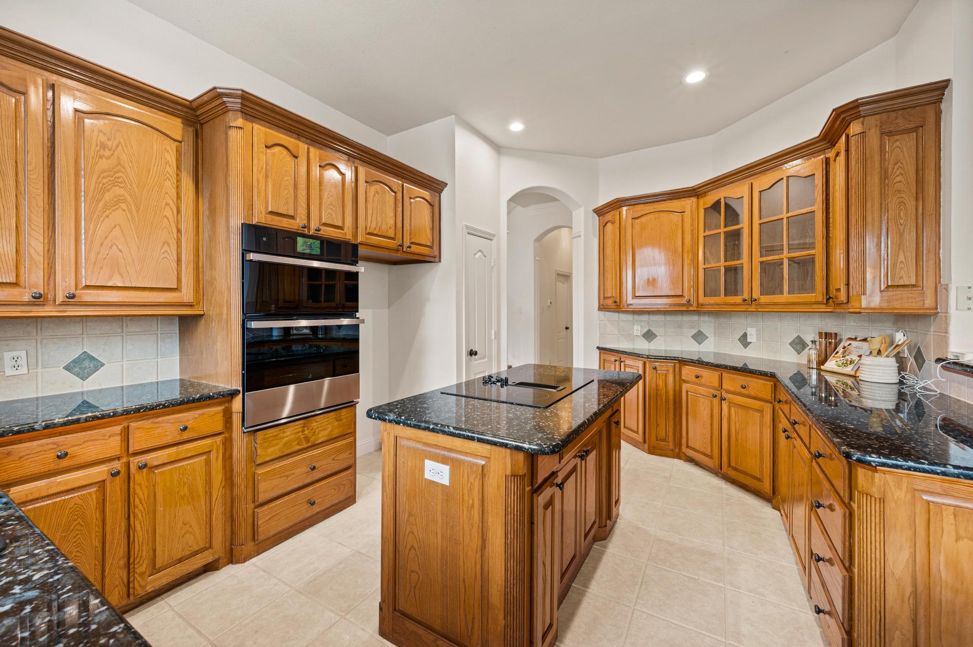 Kitchen at 7613 Woodhaven Drive, featuring granite countertops, center island, wood cabinetry, and spacious pantry