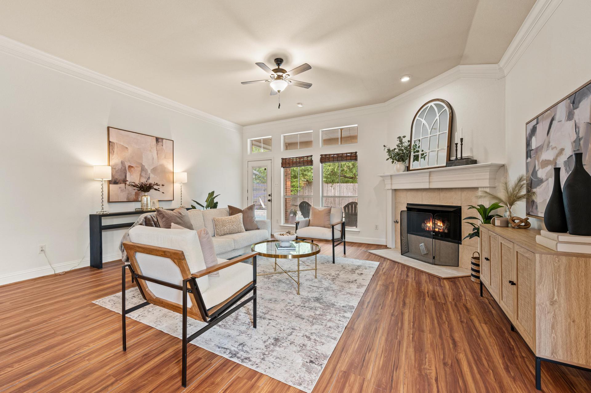 Living room with fireplace, windows overlooking the backyard, and access to the outdoor area