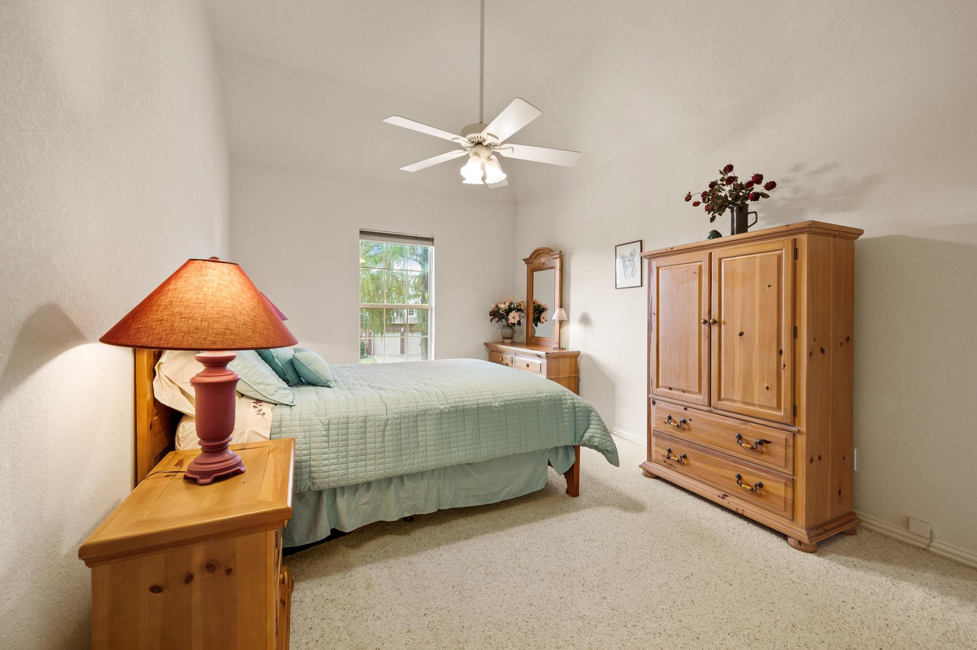 Third bedroom with carpeted flooring, ceiling fan, and wood furnishings at 7626 Lakecrest Circle