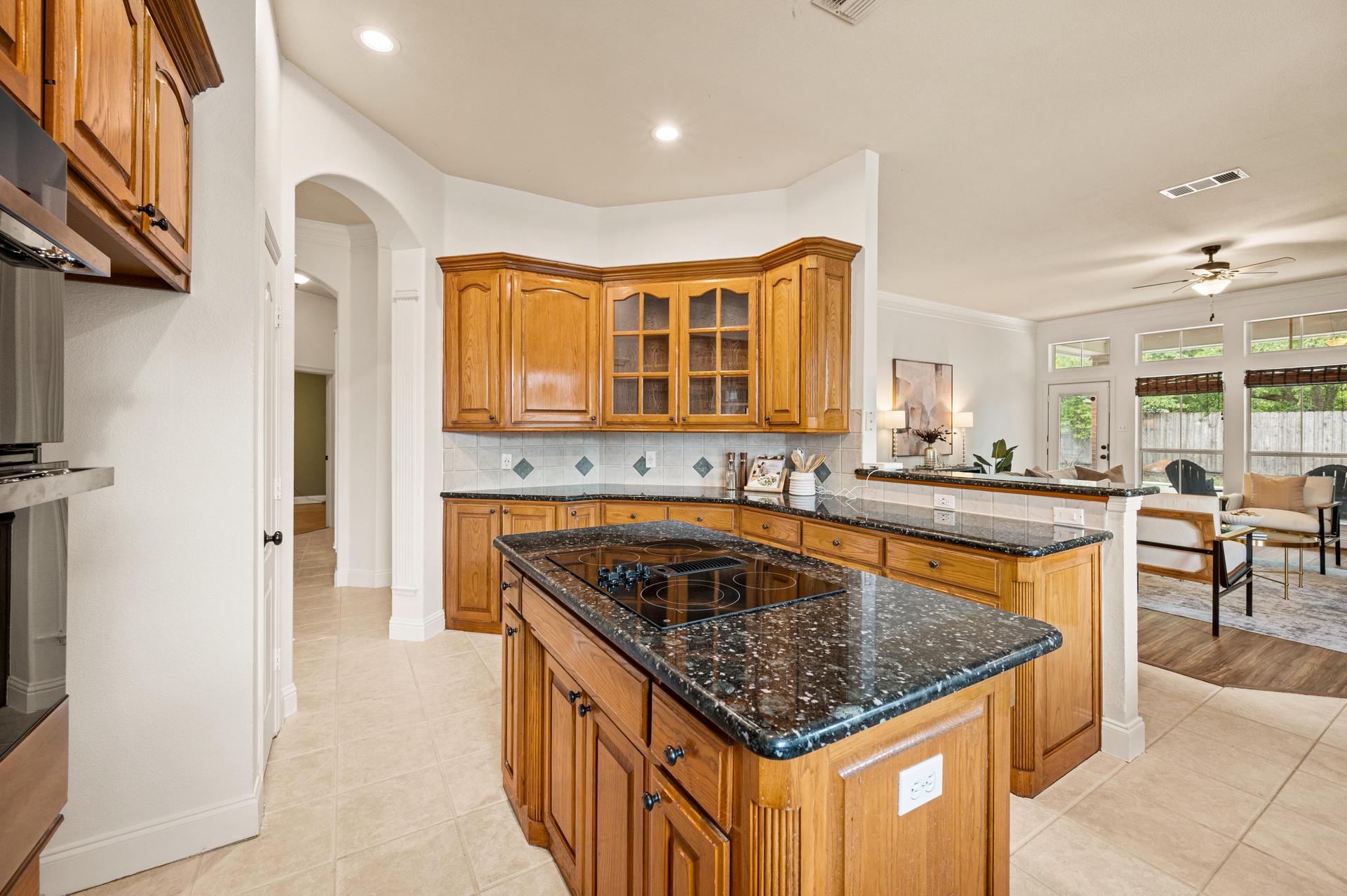 Kitchen at 7613 Woodhaven Drive, featuring granite countertops, center island, wood cabinetry, and spacious pantry