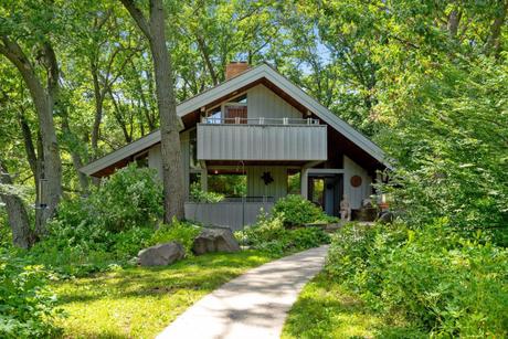 Architectural home on a wooded Stillwater lot in full summer green, with landscaped walkway and mature oaks