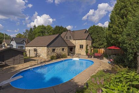 Stillwater, Minnesota stone home with an open in-ground pool, patio, and blue summer sky